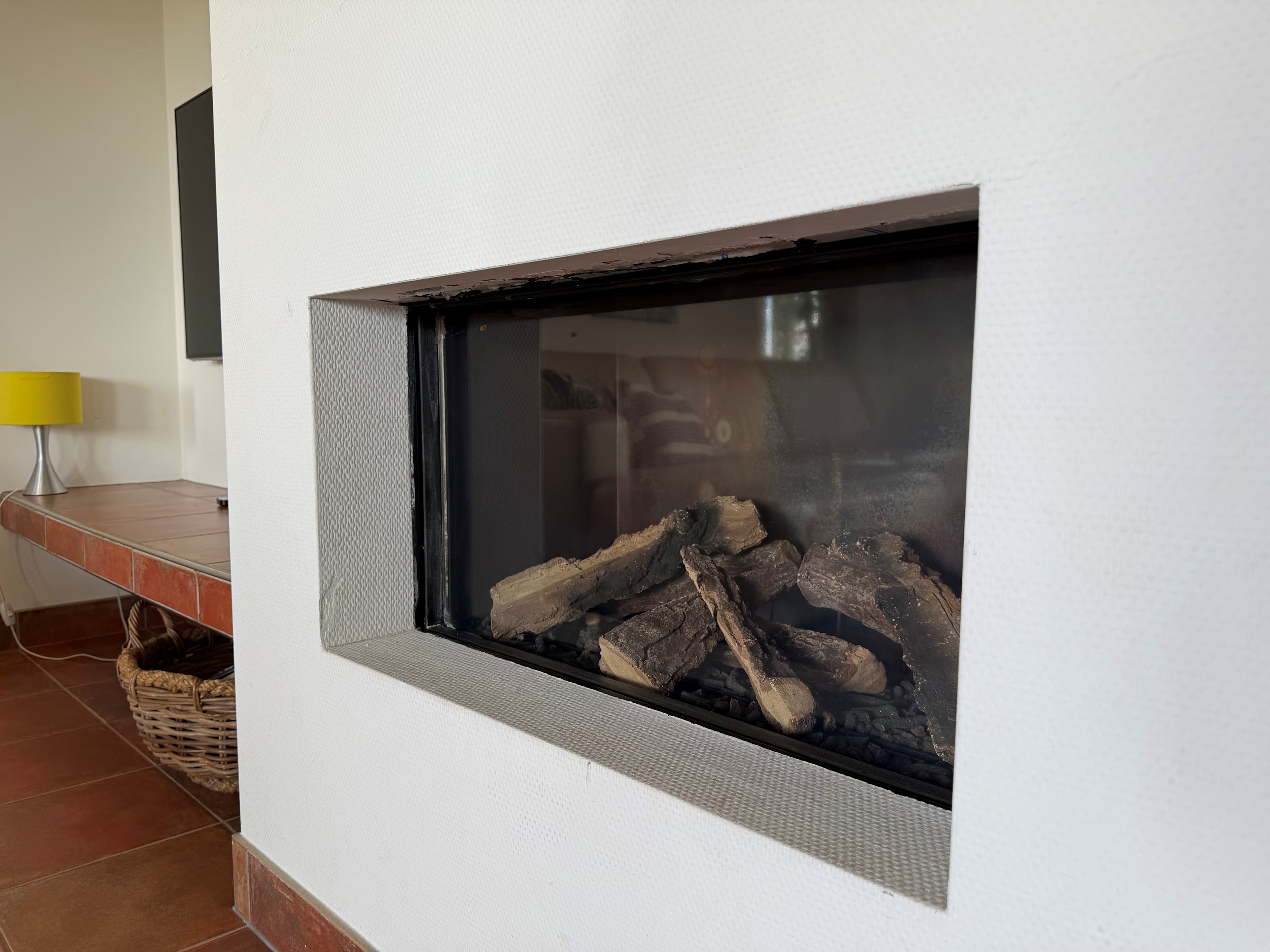 Element van een moderne open haard met zicht op houtblokken in een recreatiewoning