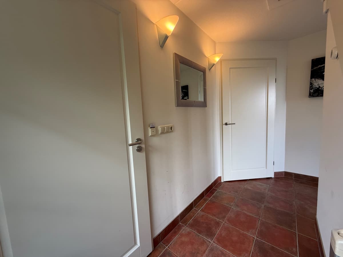 Entree van de recreatiewoning met tegels, spiegels en deuren aan beide zijden.