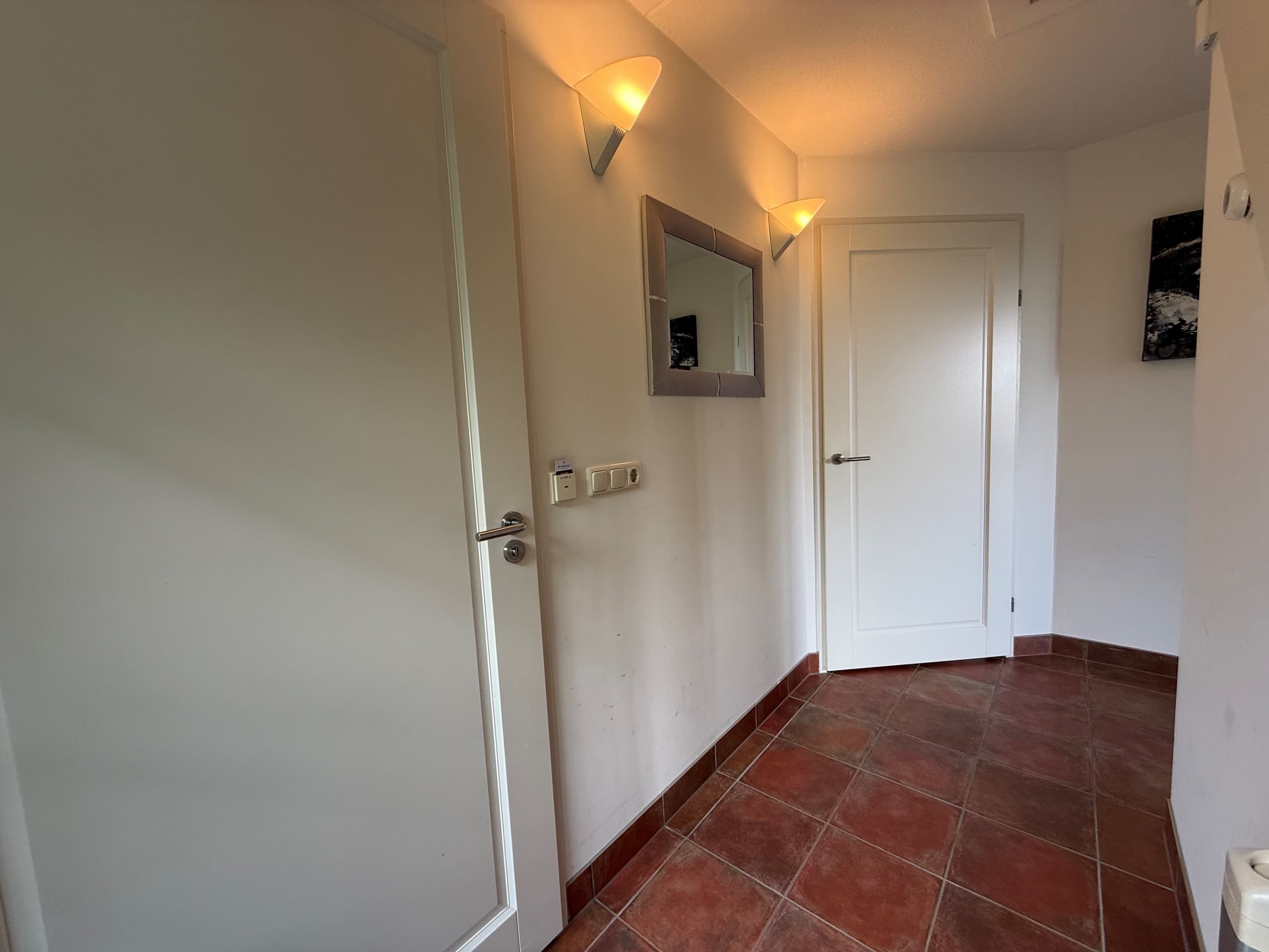 Entree van de recreatiewoning met tegels, spiegels en deuren aan beide zijden.