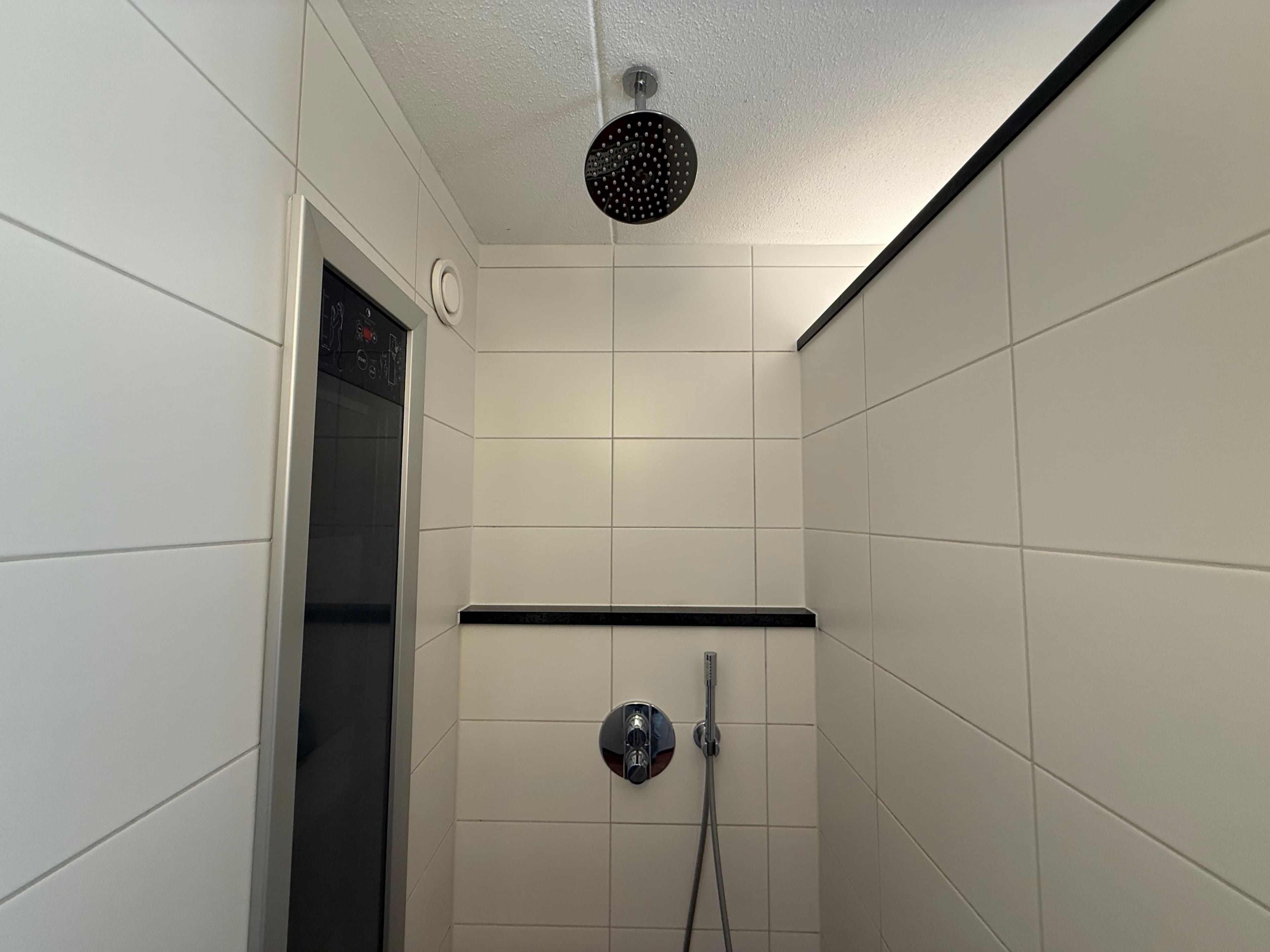 Moderne badkamer met een inloopdouche, tegelwanden en een regendouche boven.