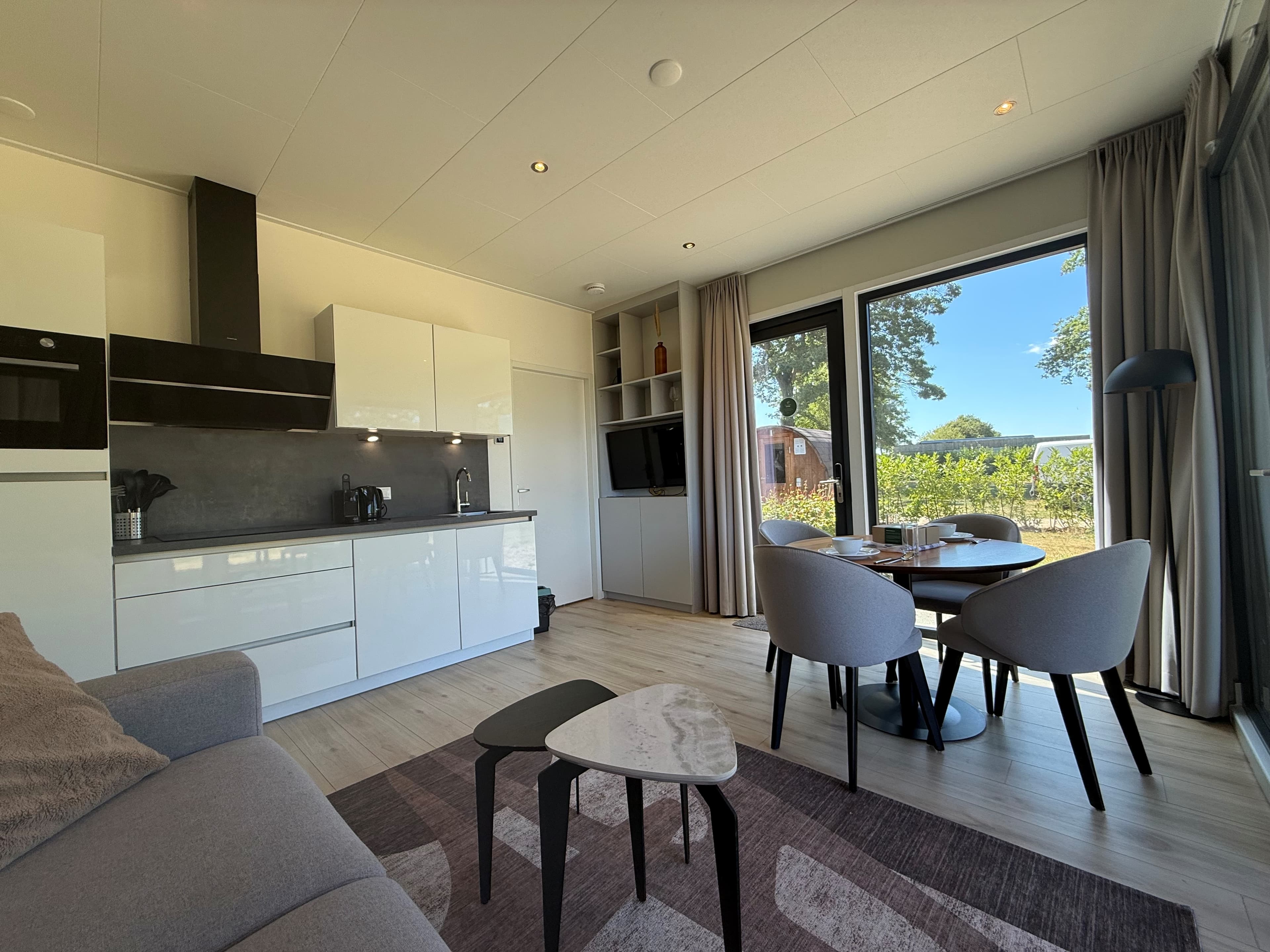 Moderne woonkamer met keuken, eetruimte en grote ramen met uitzicht op de tuin en omgeving