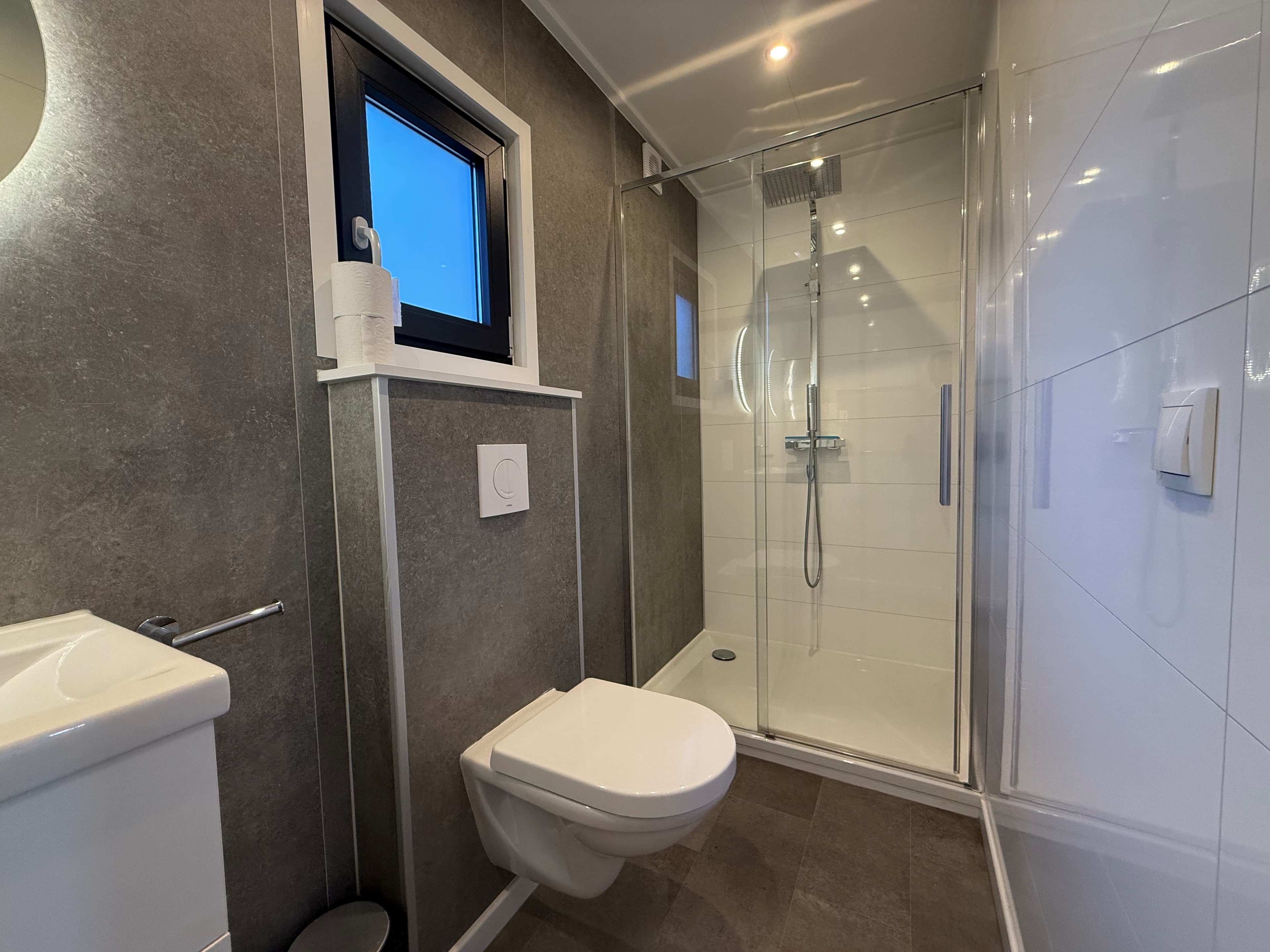 Moderne badkamer met douche, toilet en wastafel, afgewerkt met grijze en witte tegels