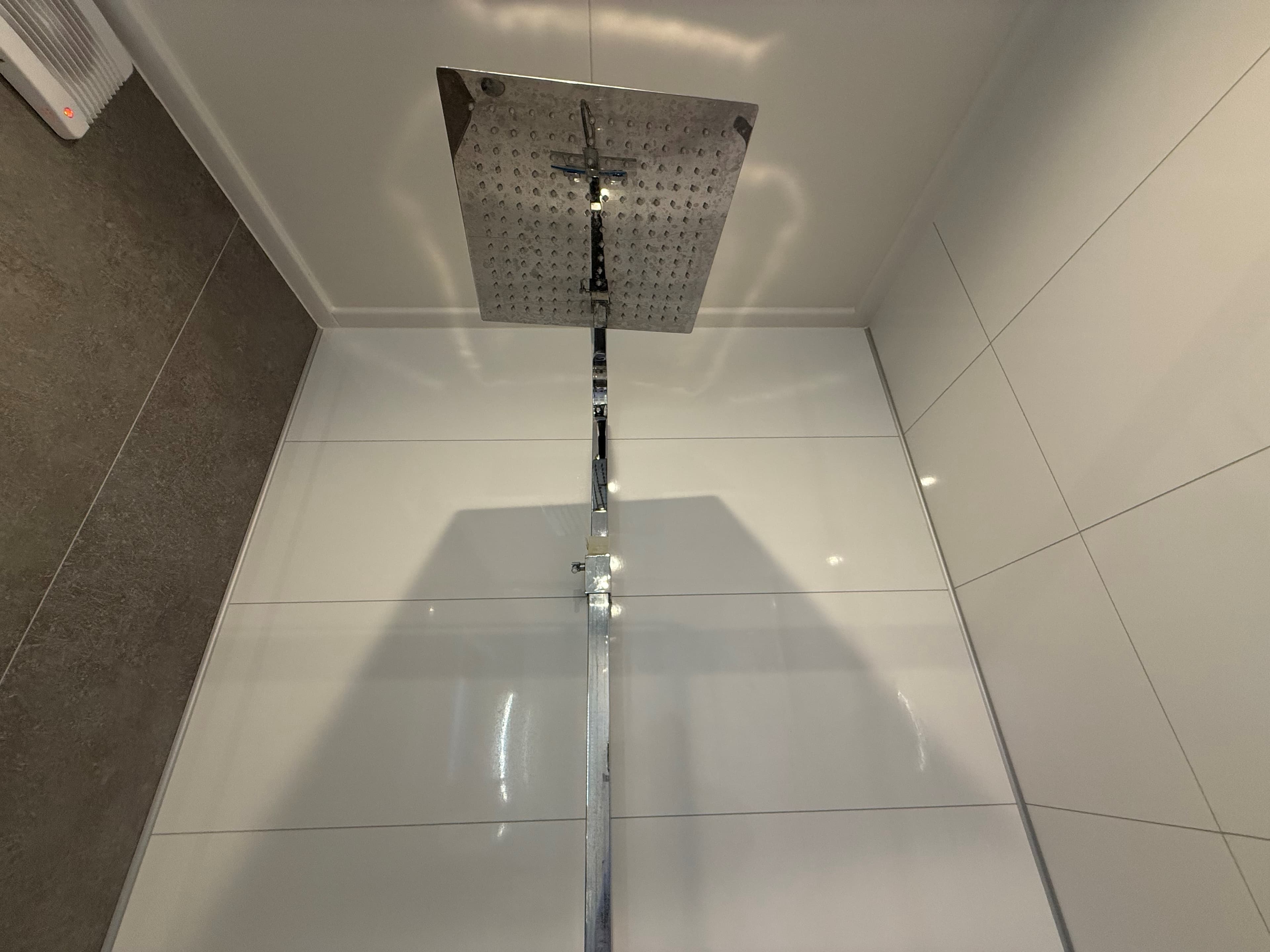 Inloopdouche met een grote regendouchekop en betegelde wanden in een lichte kleur.