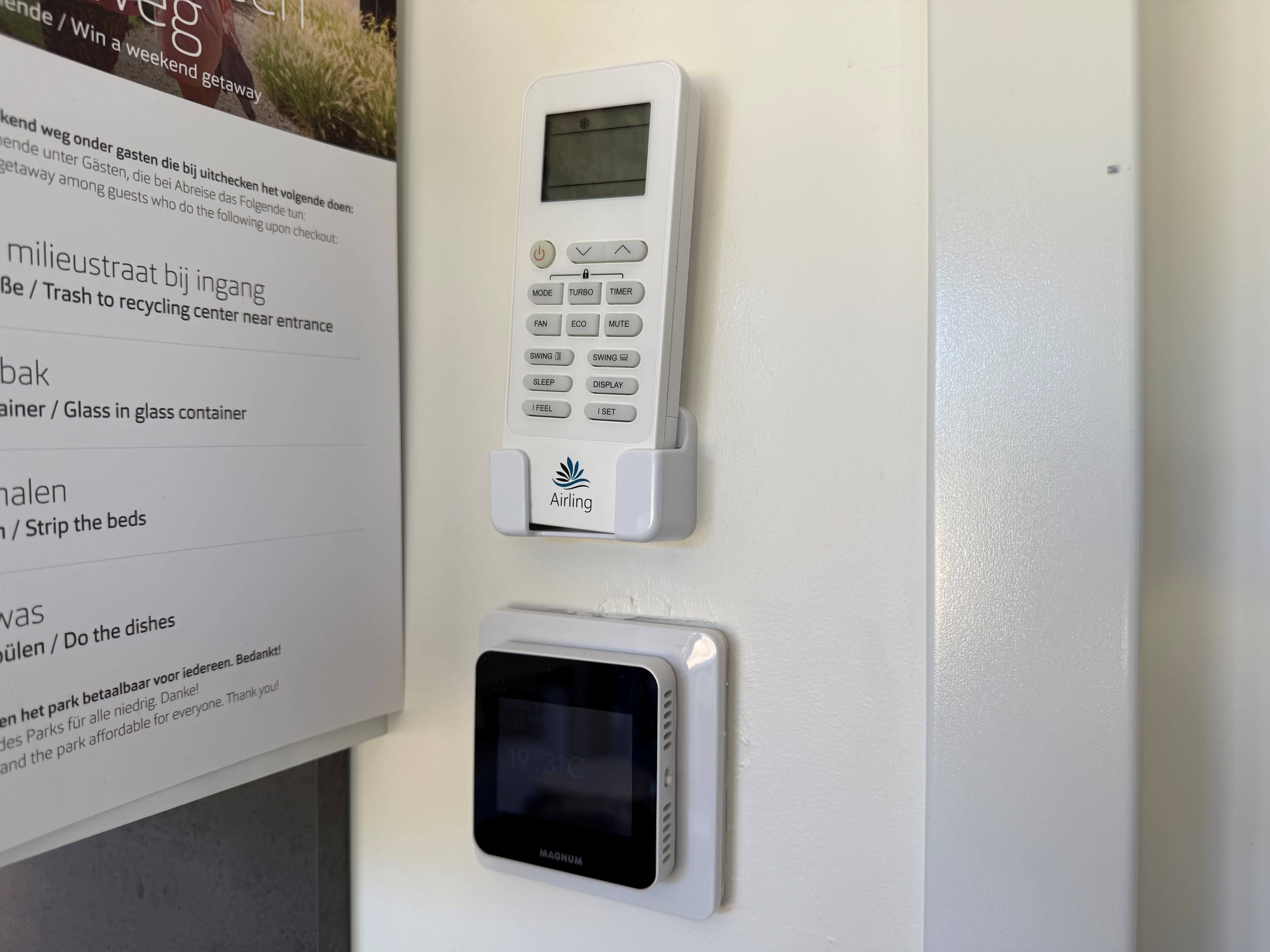 Afbeelding van een wand met een afstandsbediening en thermostaat, beide bevestigd aan een witte muur.