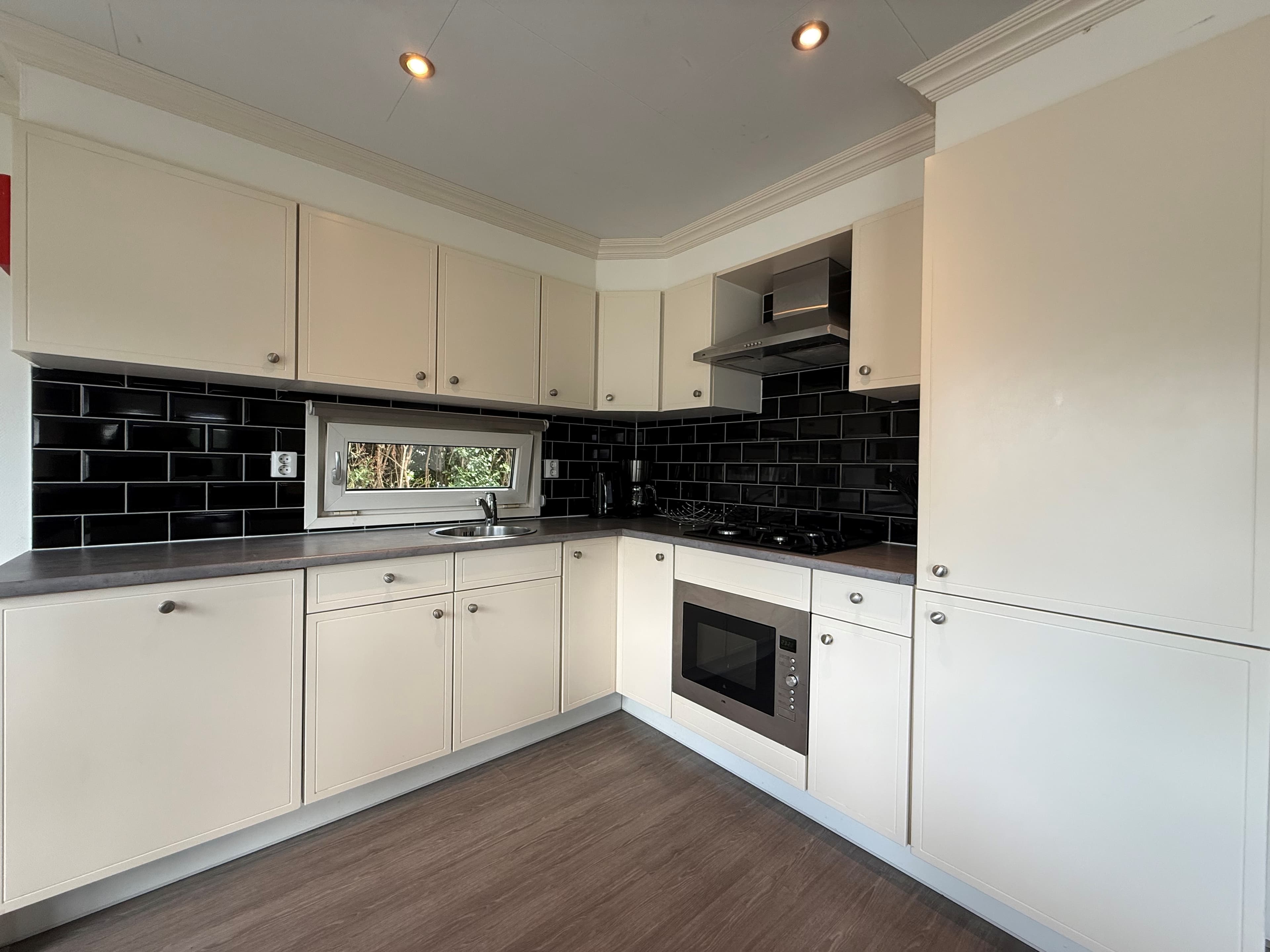 Modern ingerichte keuken met witte kasten, zwarte tegels en inbouwapparatuur in een recreatiewoning