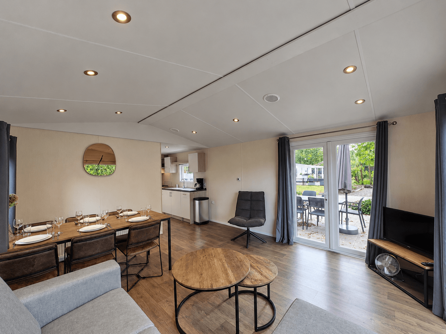 Moderne recreatiewoning met eetgedeelte, zithoek en openslaande deuren naar het terras met tuinmeubilair