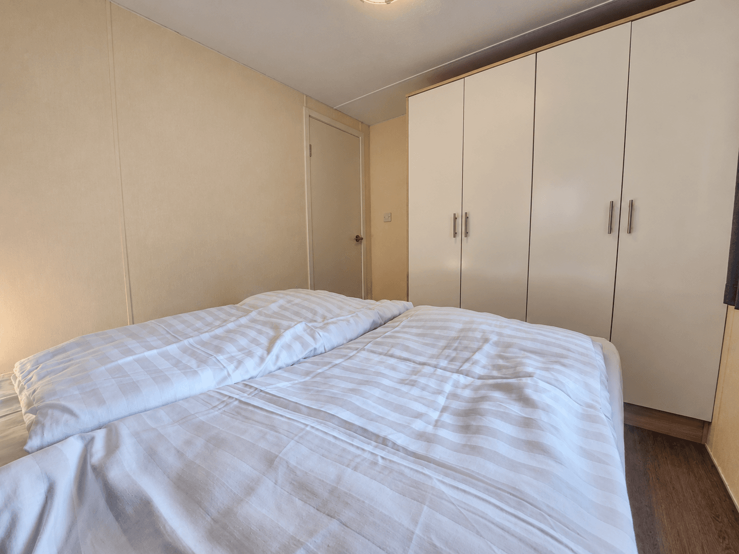 Slaapkamer met een tweepersoonsbed en een witte kast tegen de muur