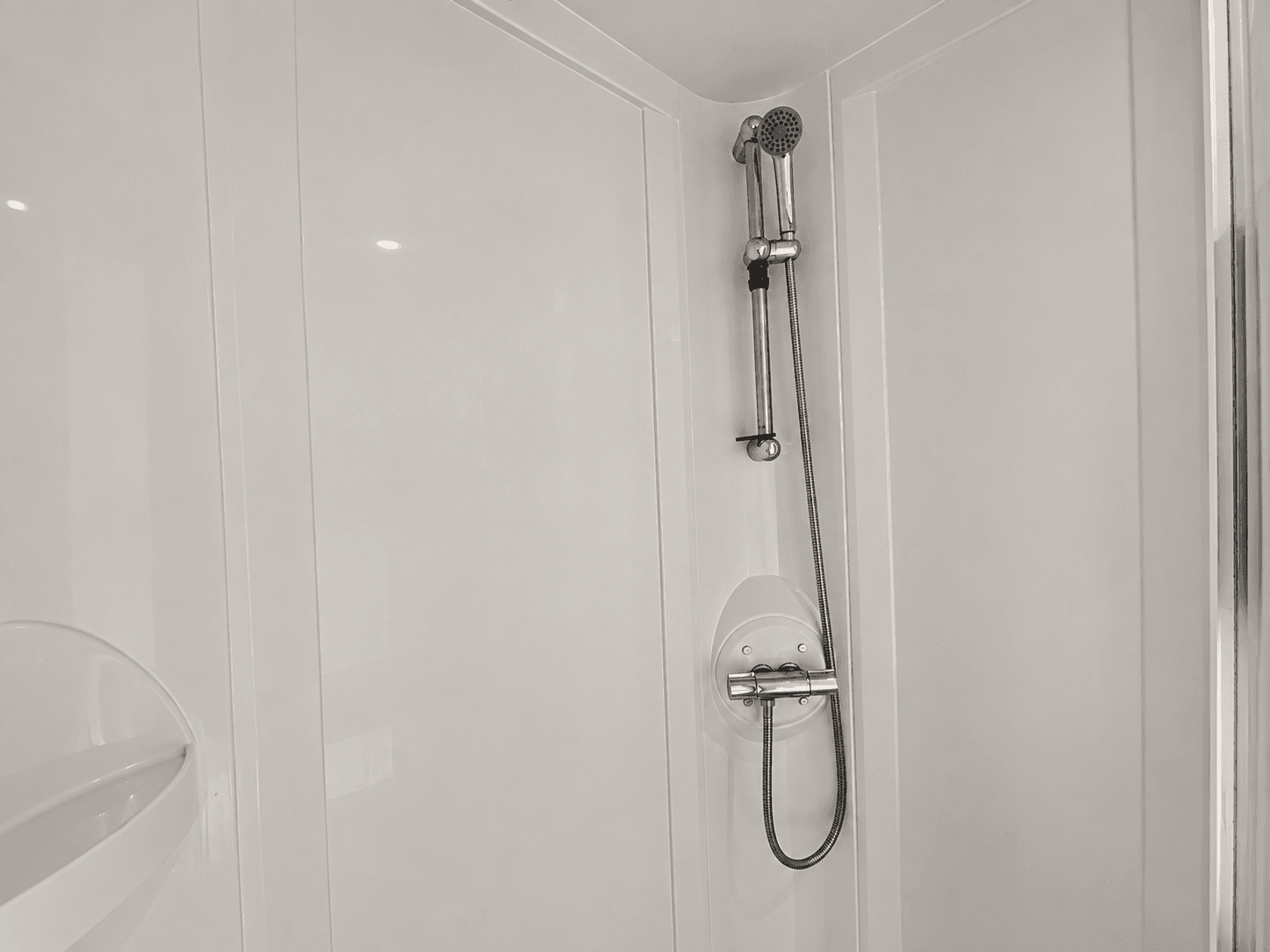 Moderne inloopdouche met regendouche en handdouche, wit tegelwerk en minimalistisch ontwerp
