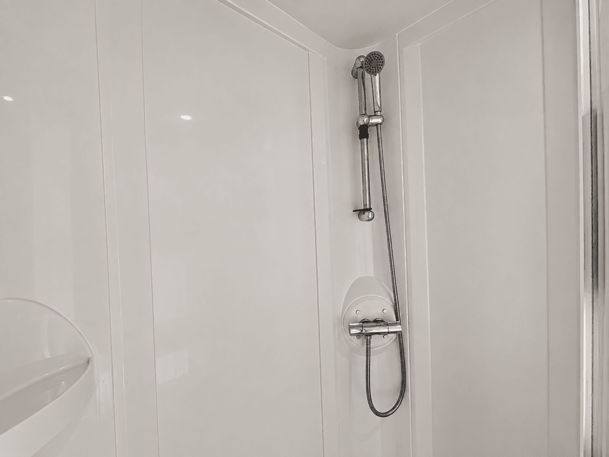 Moderne inloopdouche met regendouche en handdouche, wit tegelwerk en minimalistisch ontwerp