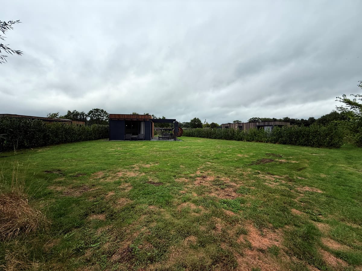Recreatiewoning met grasveld en achterliggende begroeiing op Vakantiepark Hofparken Wiltershaar, Winterswijk Kotten