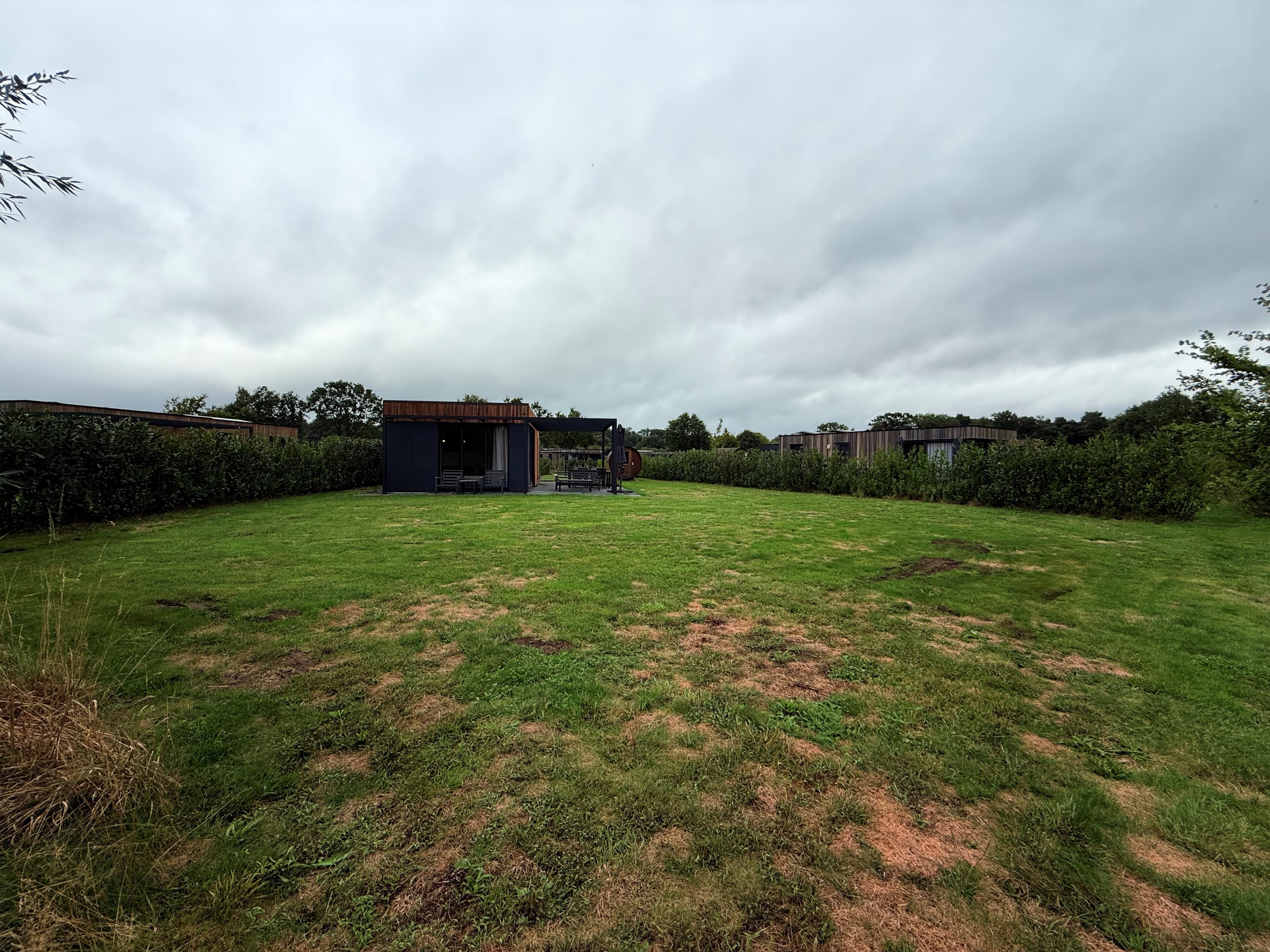 Recreatiewoning met grasveld en achterliggende begroeiing op Vakantiepark Hofparken Wiltershaar, Winterswijk Kotten