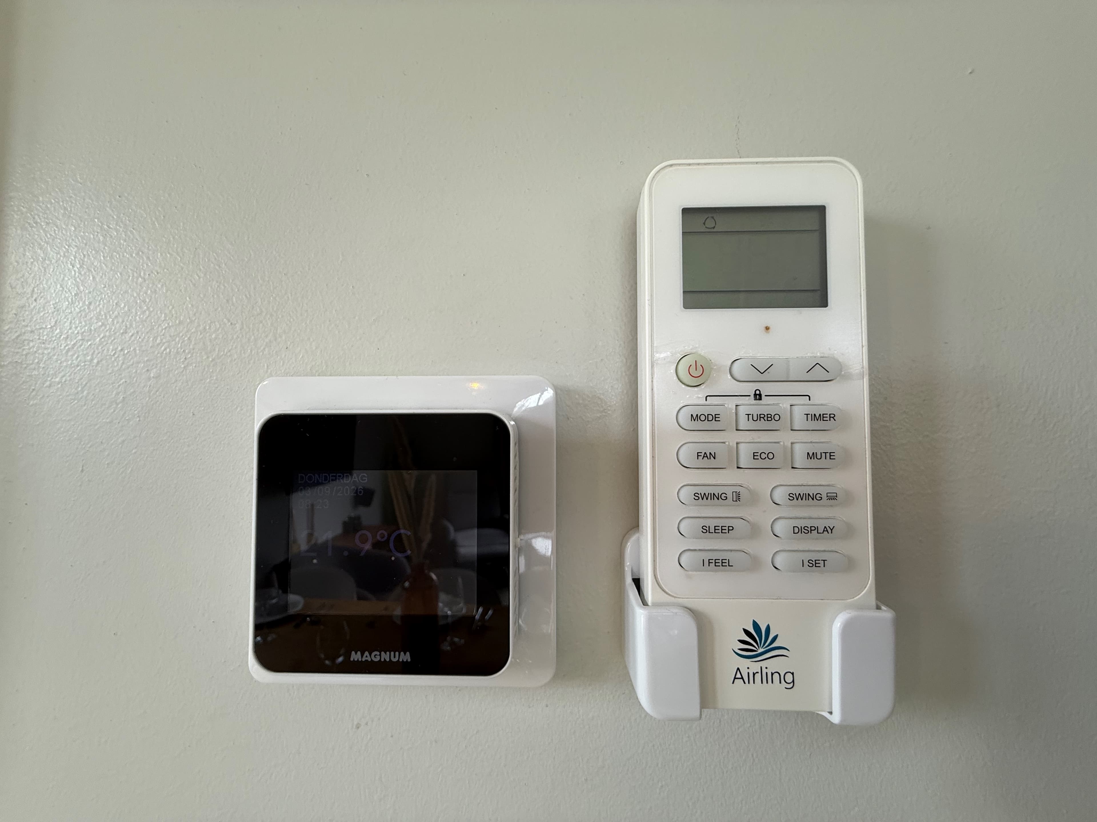Thermostaat en afstandsbediening voor klimaatregeling aan een muur in een vakantiewoning