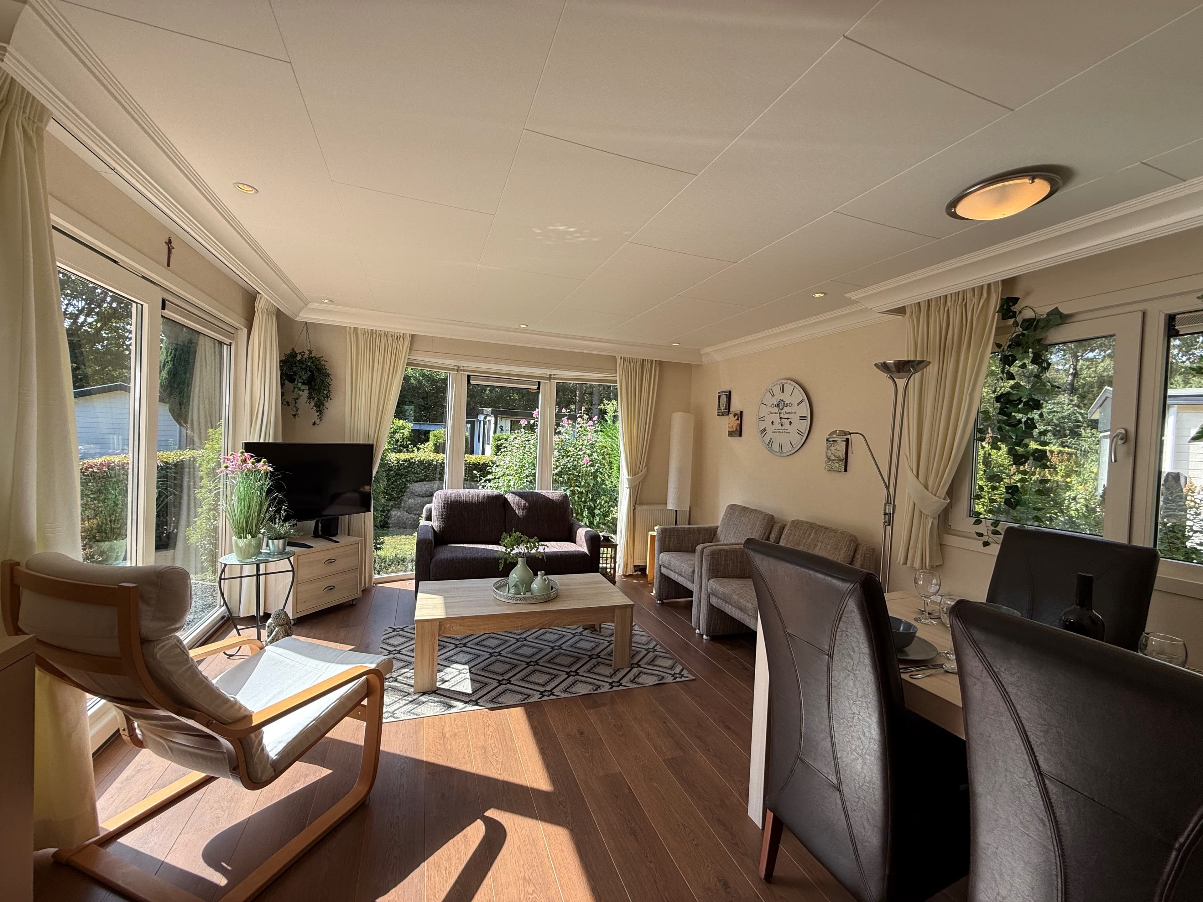 Lichte woonkamer met zithoek, eethoek en grote ramen met uitzicht op de tuin