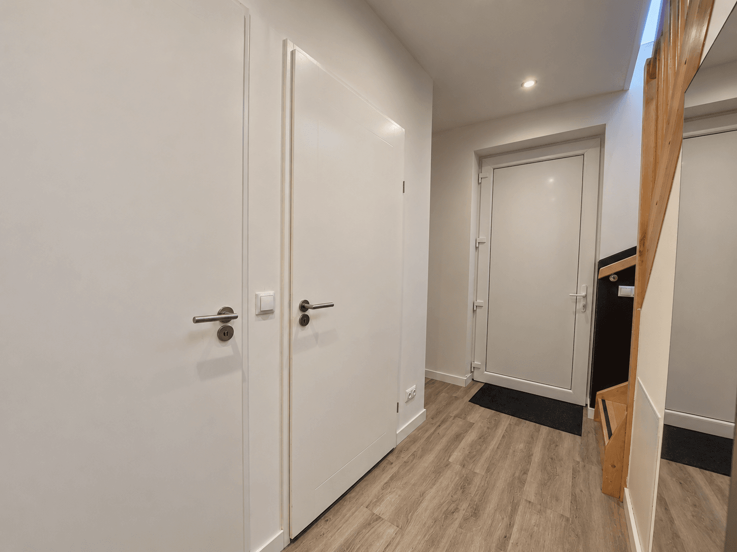 Entree van een recreatiewoning met een trap, lichte wanden en een deur naar buiten.