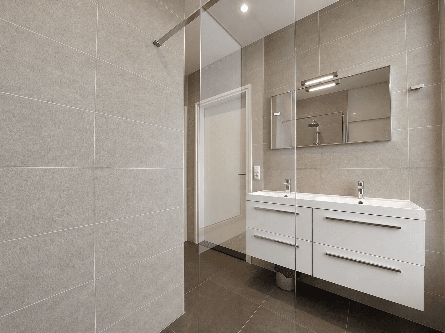 Moderne badkamer met dubbele wastafel, grote spiegel en inloopdouche in een neutrale kleurstelling