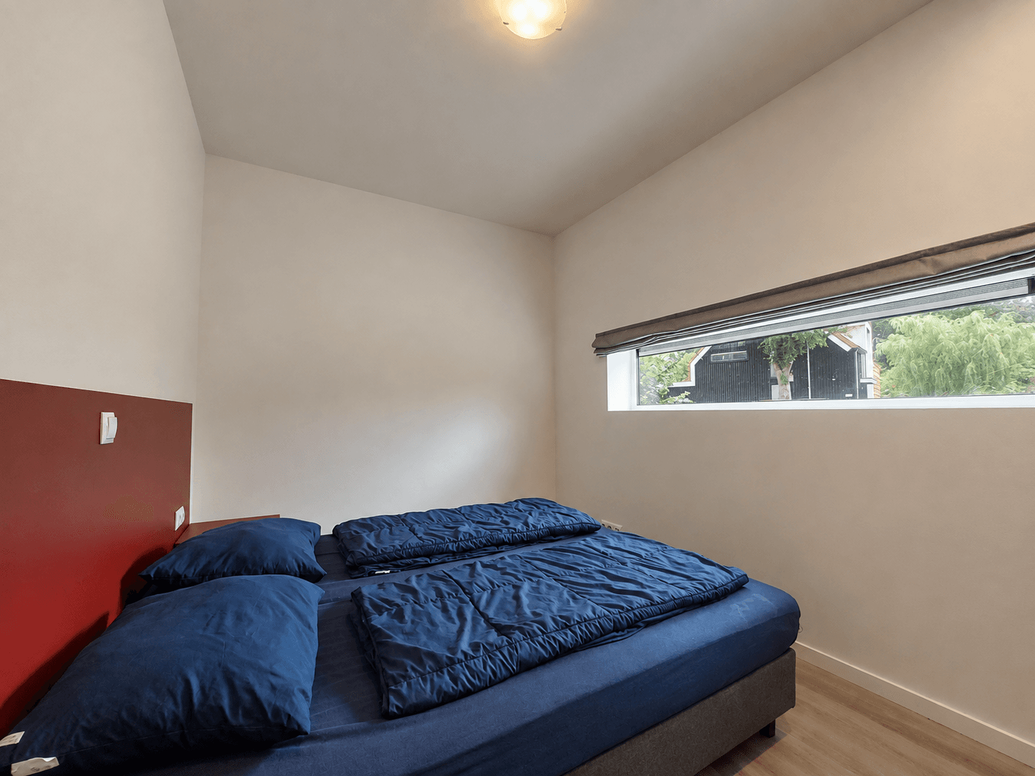 Slaapkamer met een tweepersoonsbed en raam met uitzicht op de natuur