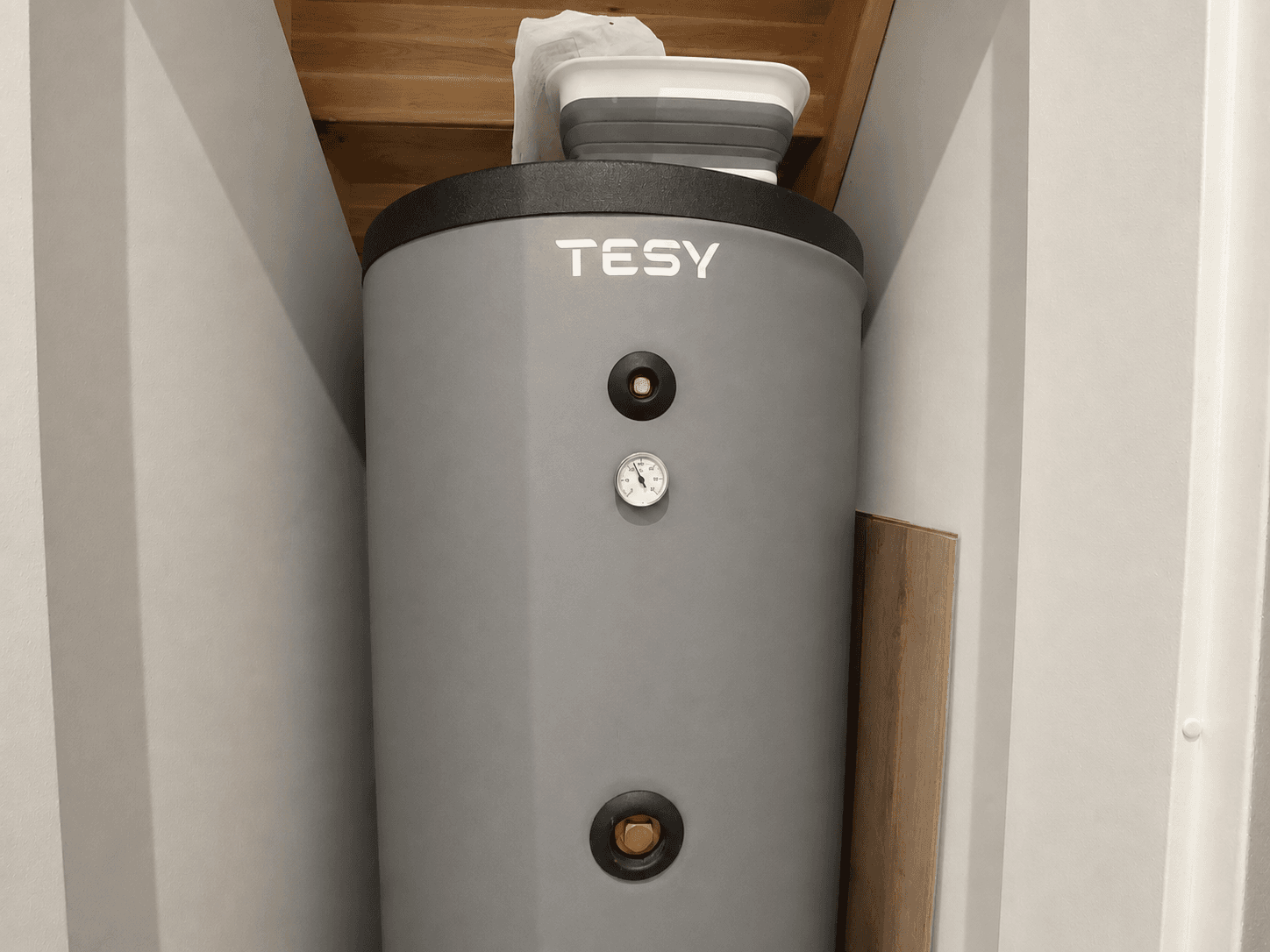 Cilindervormige boiler met drukmeter en afvoer in een neutraal gekleurde ruimte