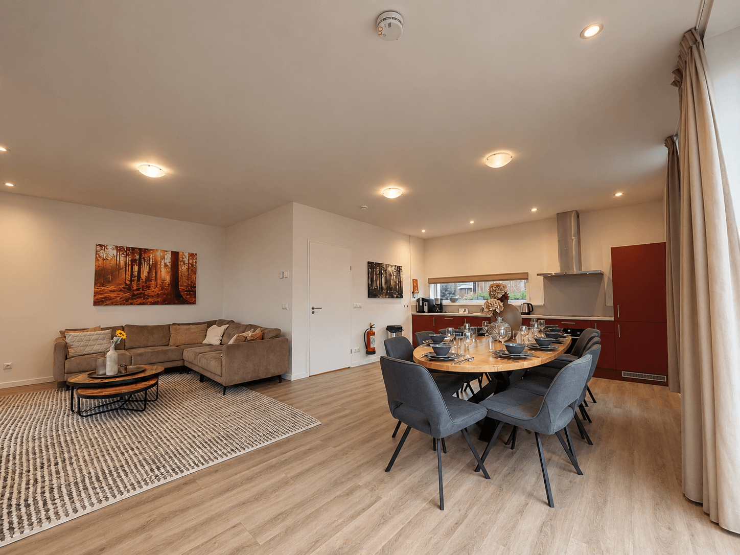Moderne woonkamer met zithoek, eettafel en open keuken, grote ramen met uitzicht op de buitenruimte