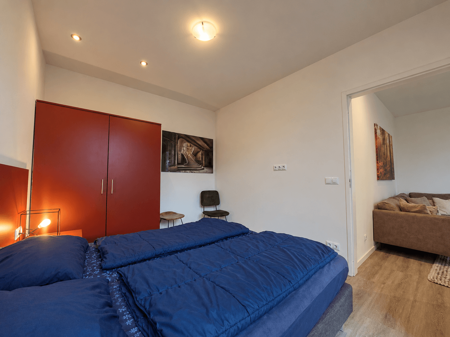 Slaapkamer met een tweepersoonsbed, rode kast, en een zitje met een stoel in een recreatiewoning.