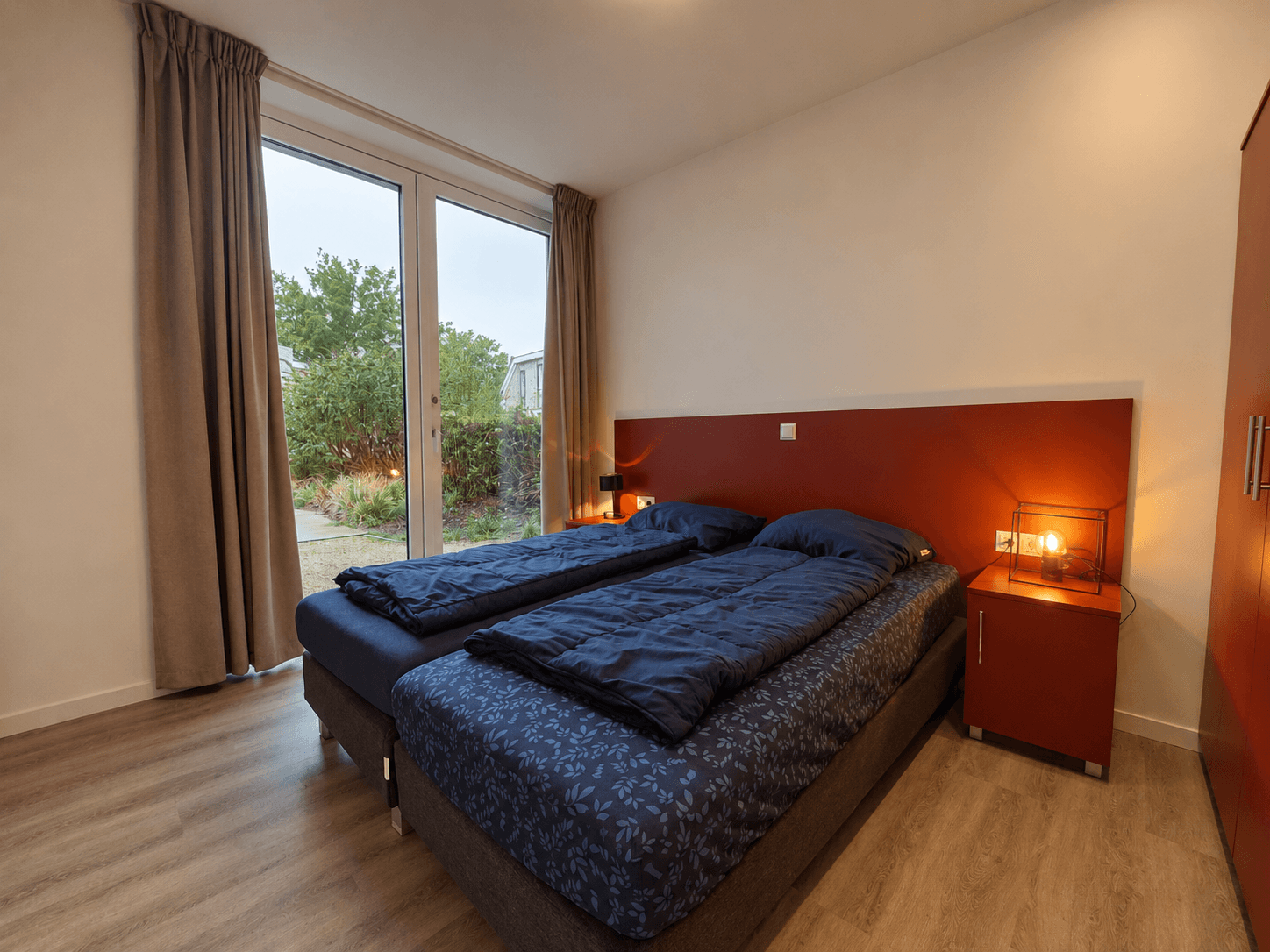 Slaapkamer met twee eenpersoonsbedden, nachtkastjes en raam met uitzicht op groene omgeving.