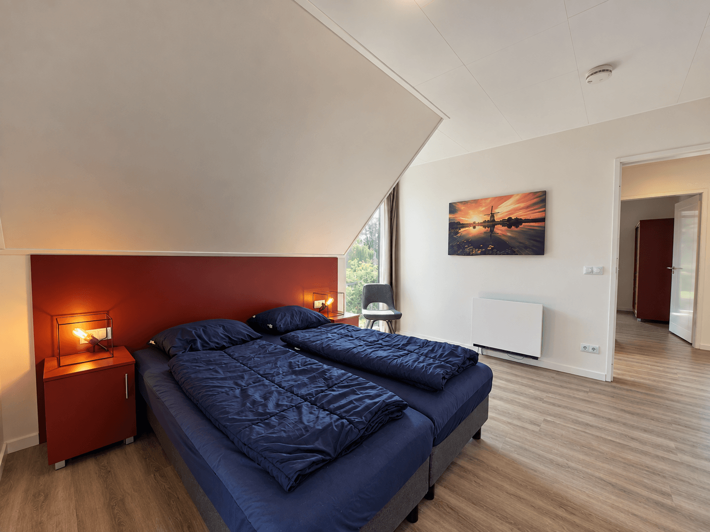 Slaapkamer met twee eenpersoonsbedden, een kast en een raam met uitzicht op de natuur
