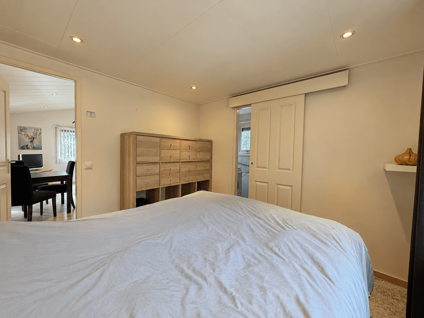 Sfeervolle slaapkamer met een groot bed, kastenwand en toegang tot een andere ruimte en badkamer