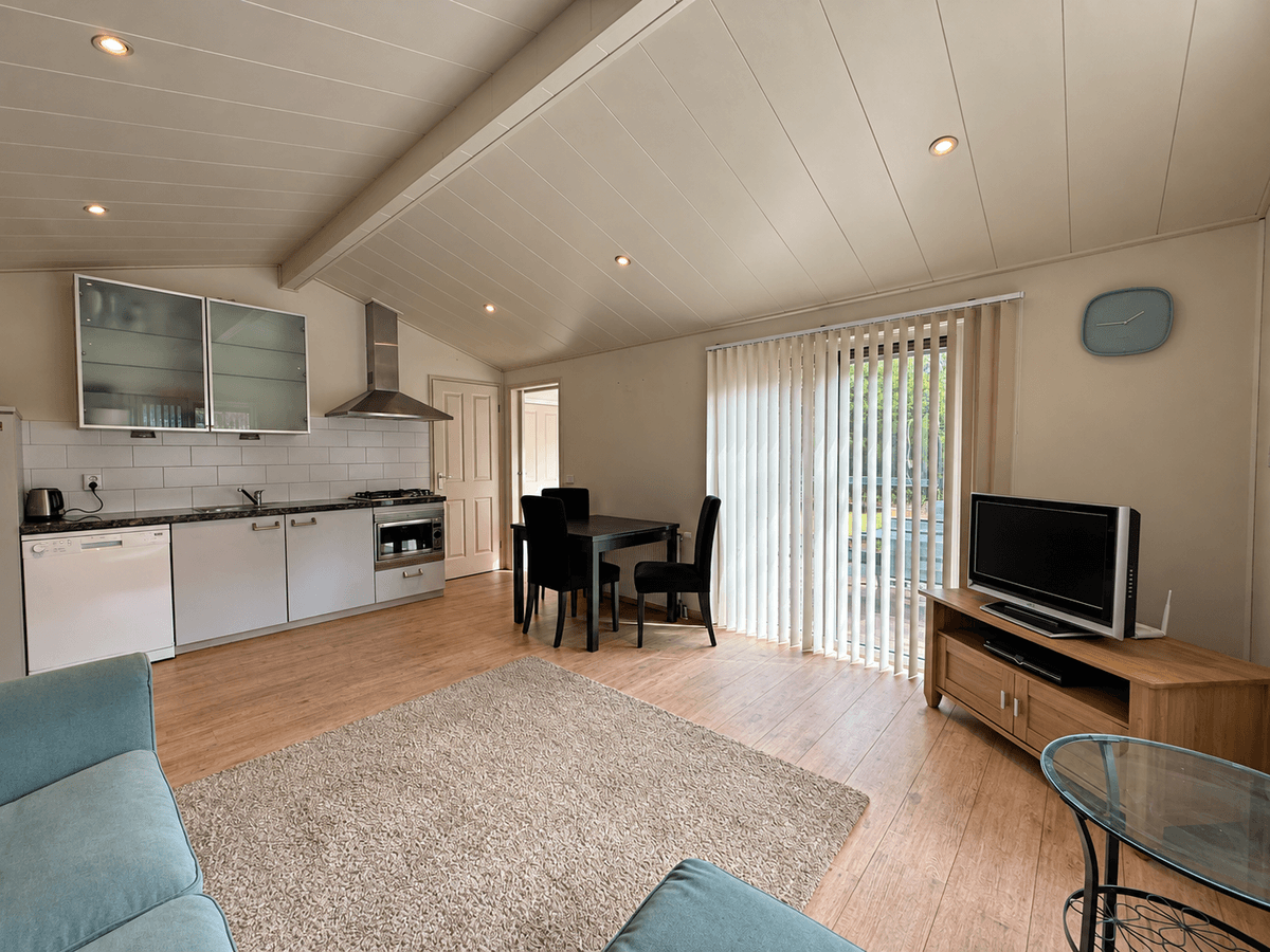 Open woonkamer met keuken, eettafel, zithoek en schuifdeur naar de buitenruimte met veel natuurlijk licht