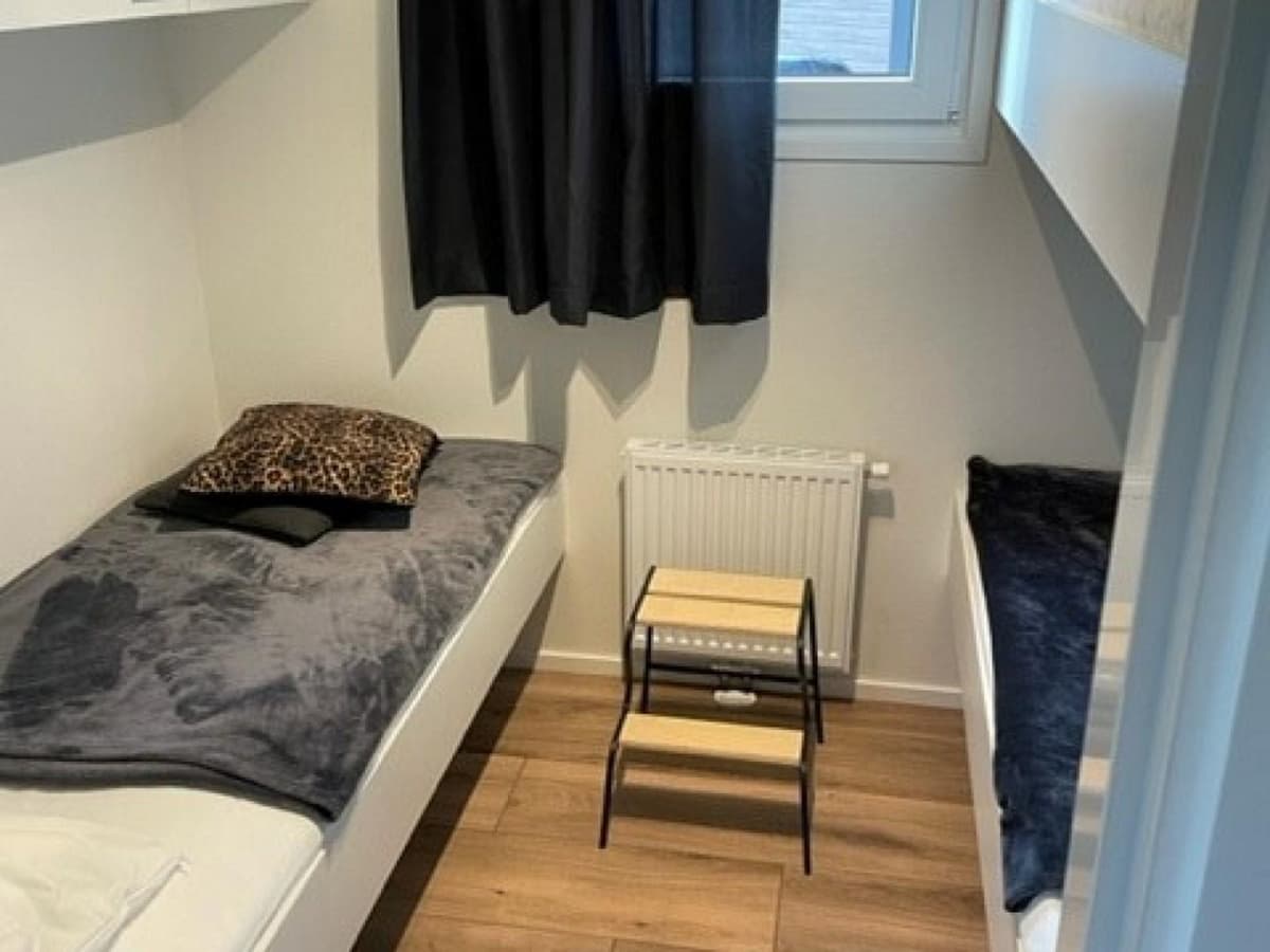 Slaapkamer met twee eenpersoonsbedden, een klein tafeltje en een radiator tegen de wand.