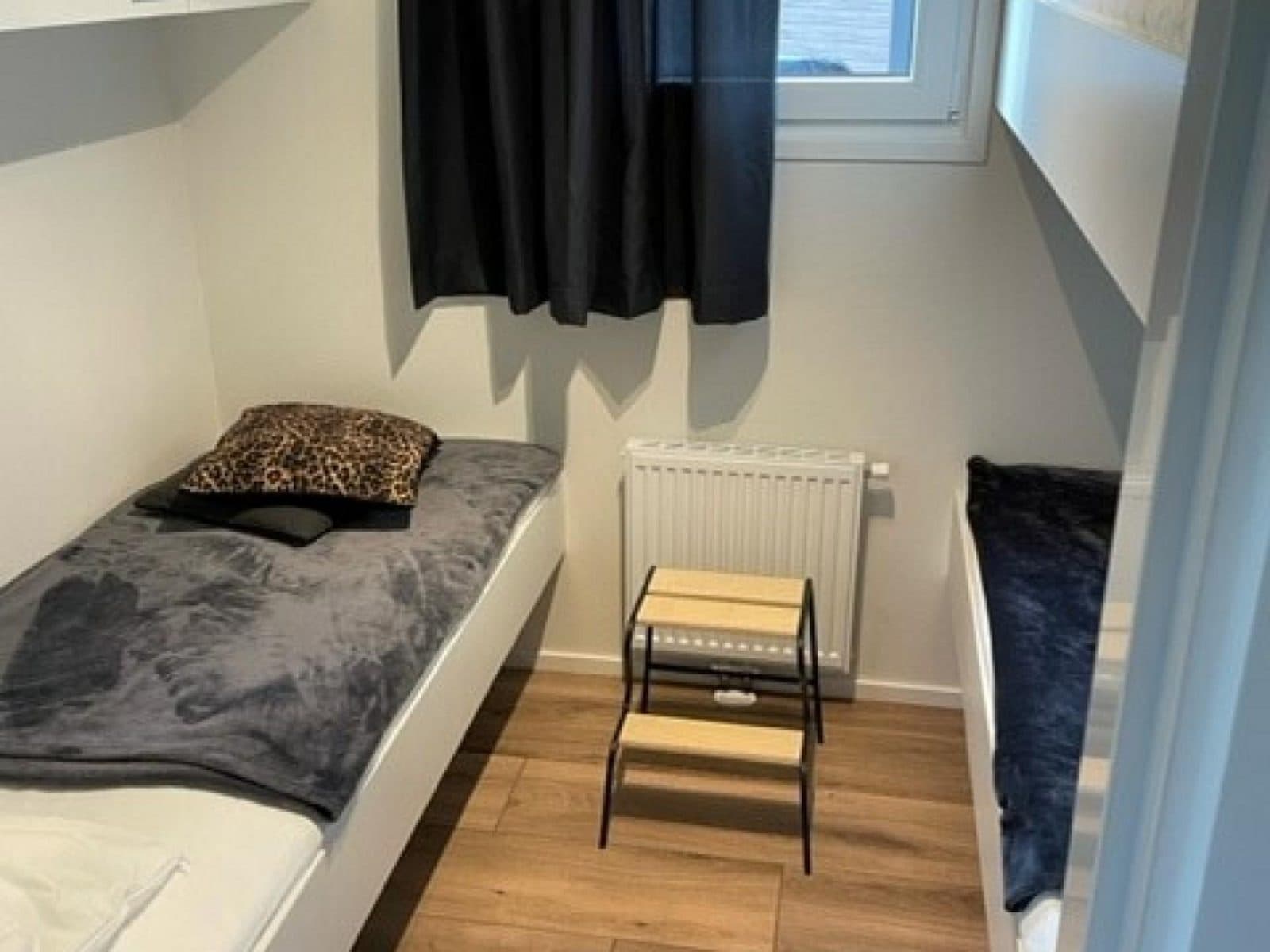 Slaapkamer met twee eenpersoonsbedden, een klein tafeltje en een radiator tegen de wand.