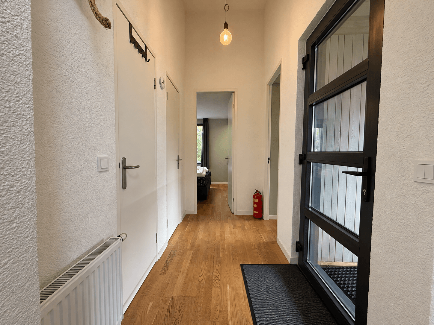 Ingang van de recreatiewoning met een lange gang en deuren naar andere ruimtes, mooi houten vloeren en een moderne deur.