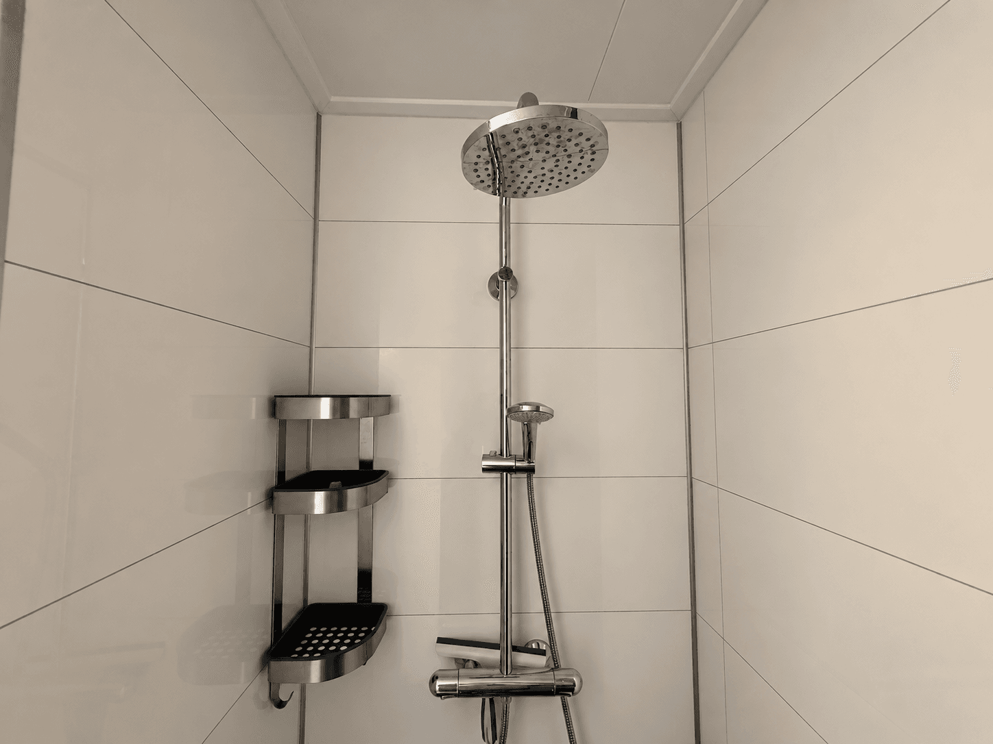 Moderne douche met regendouchekop en wandplanken in een betegelde ruimte