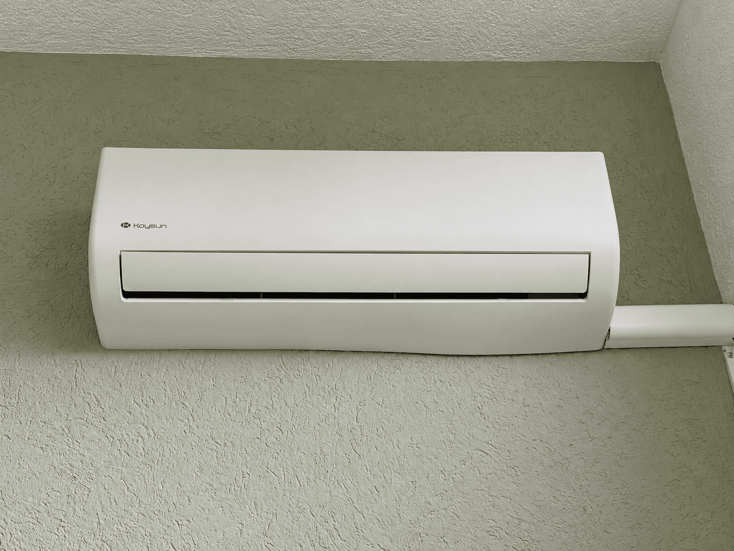 Airconditioning unit aan de muur in een recreatiewoning met een groene wand.