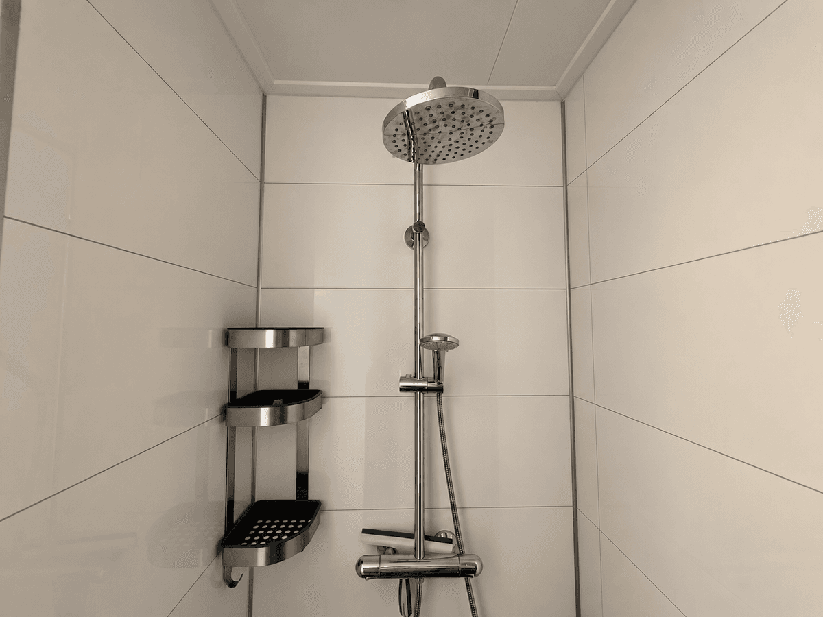 Moderne douche met regendouchekop en wandplanken in een betegelde ruimte