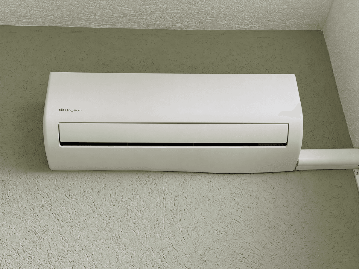 Airconditioning unit aan de muur in een recreatiewoning met een groene wand.