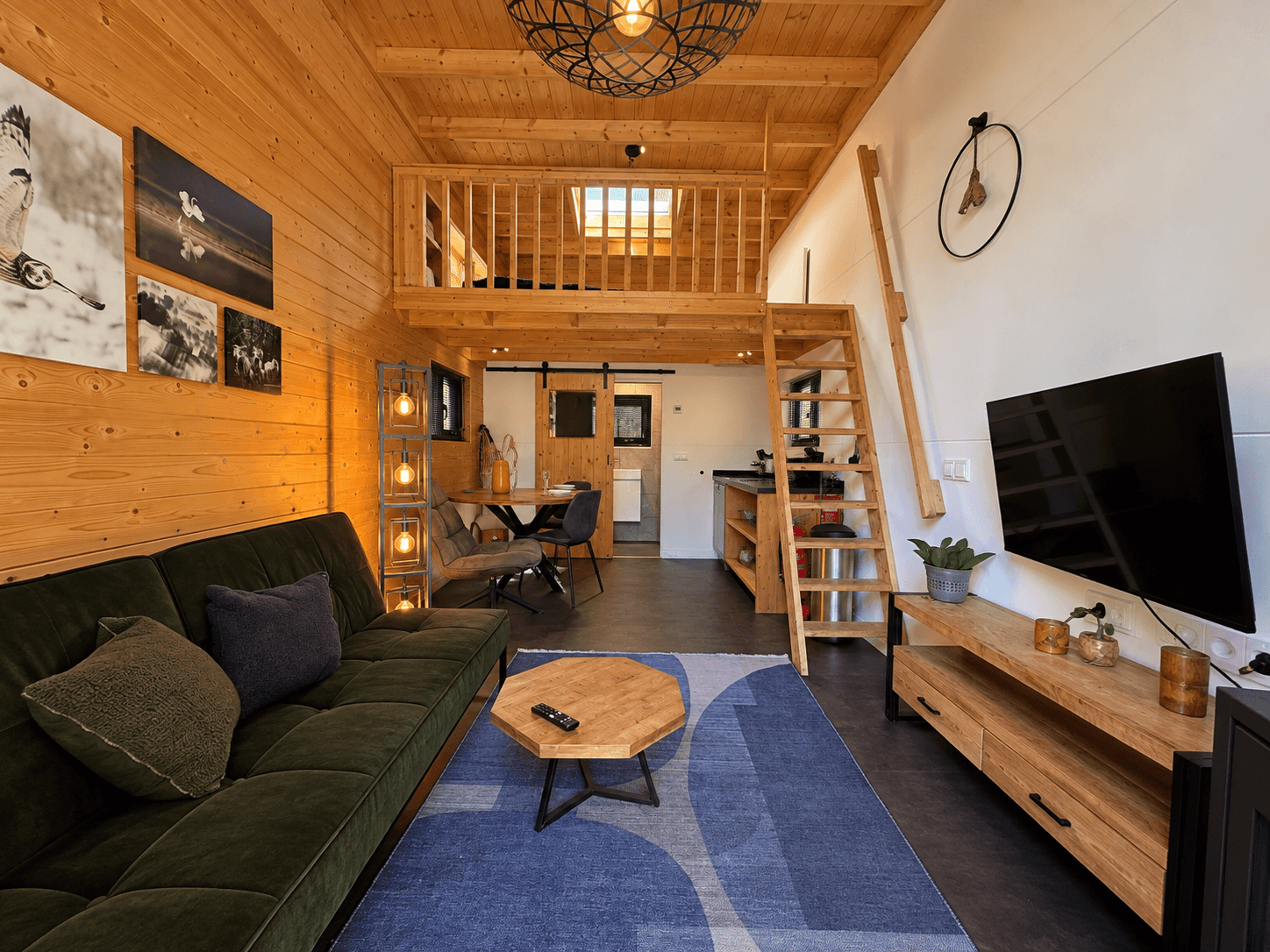 Gezellige recreatiewoning met houten wandafwerking, zithoek, eettafel en open keukenruimte met trap naar vide