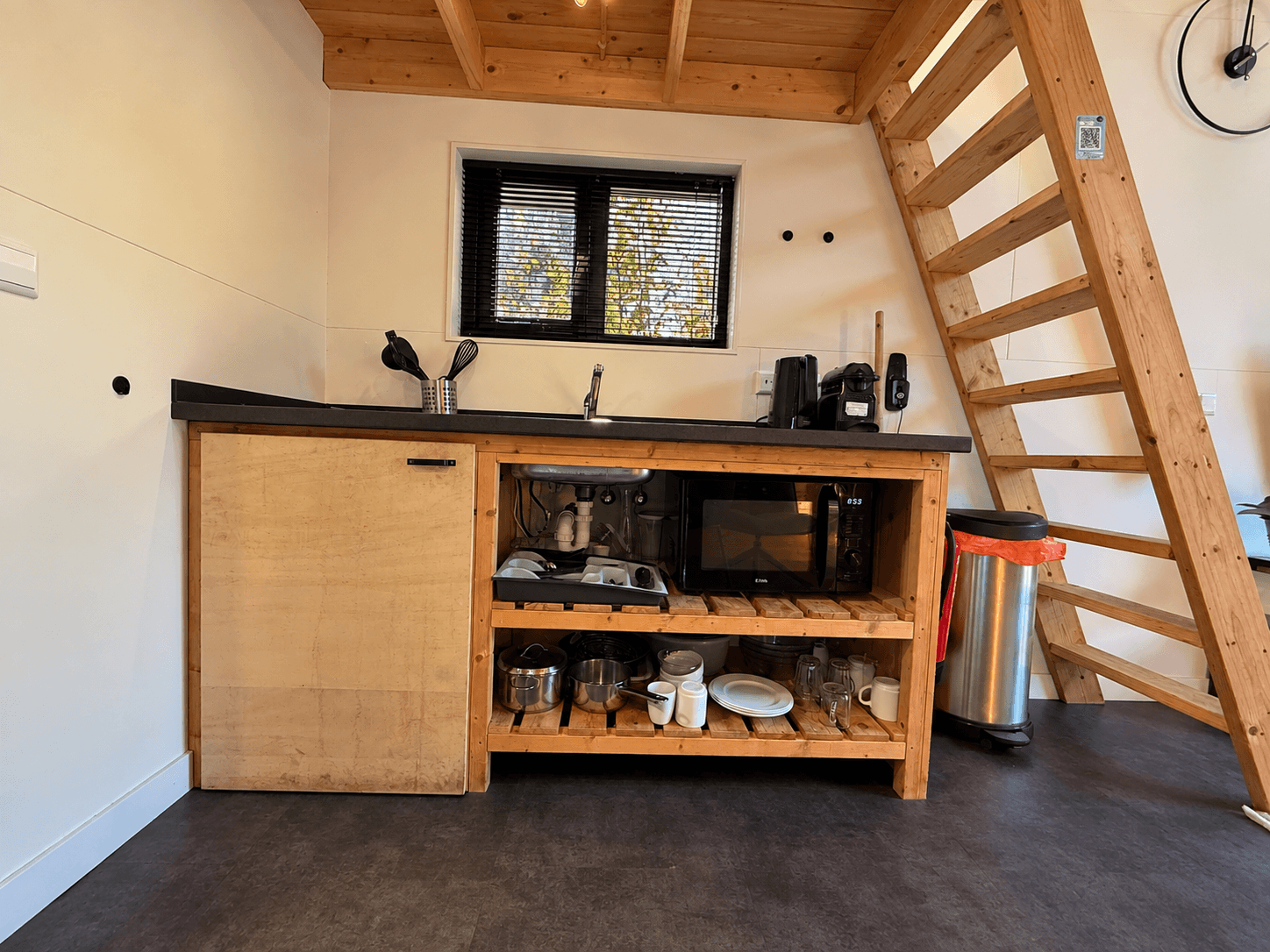 Keuken in een recreatiewoning met houten kasten, een spoelbak, een fornuis en een trap naar een bovenverdieping.