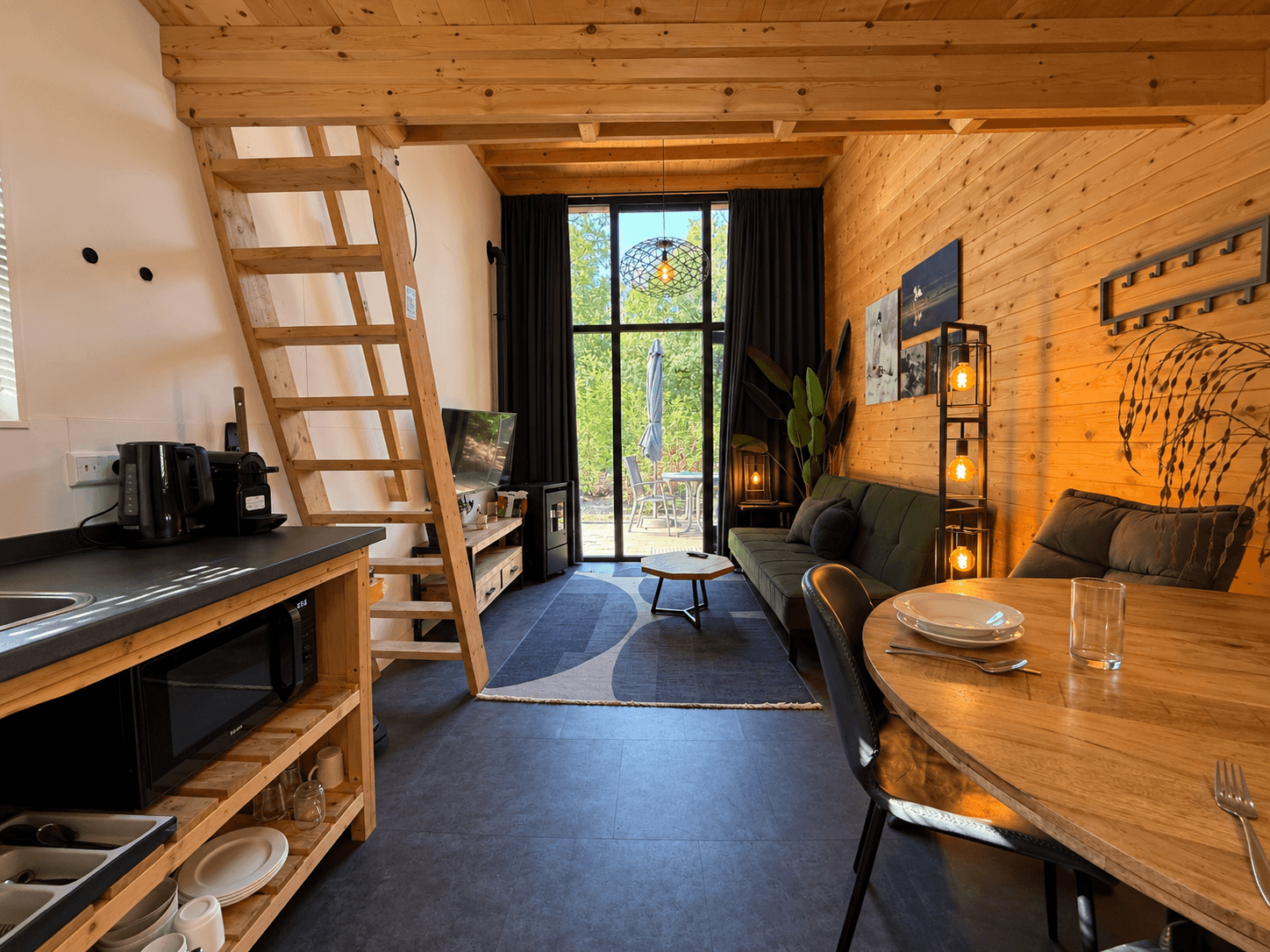In een moderne recreatiewoning met houten elementen, een zithoek, eettafel en toegang tot een terras met uitzicht op de natuu