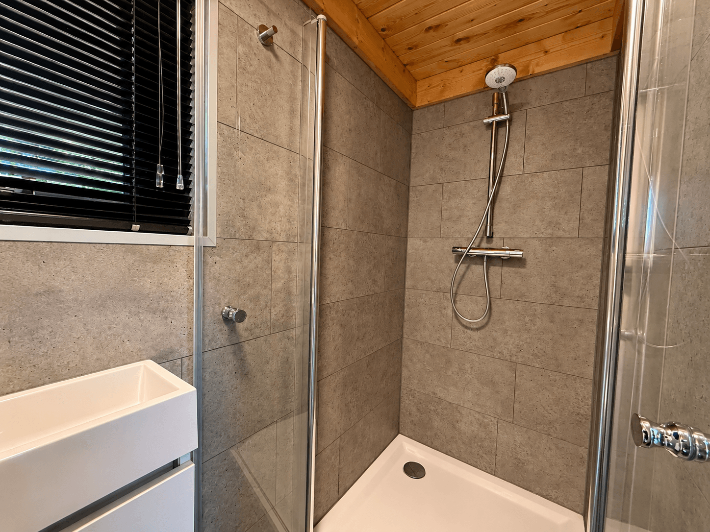 Moderne badkamer met inloopdouche, zwevend wastafelmeubel en houten plafond.