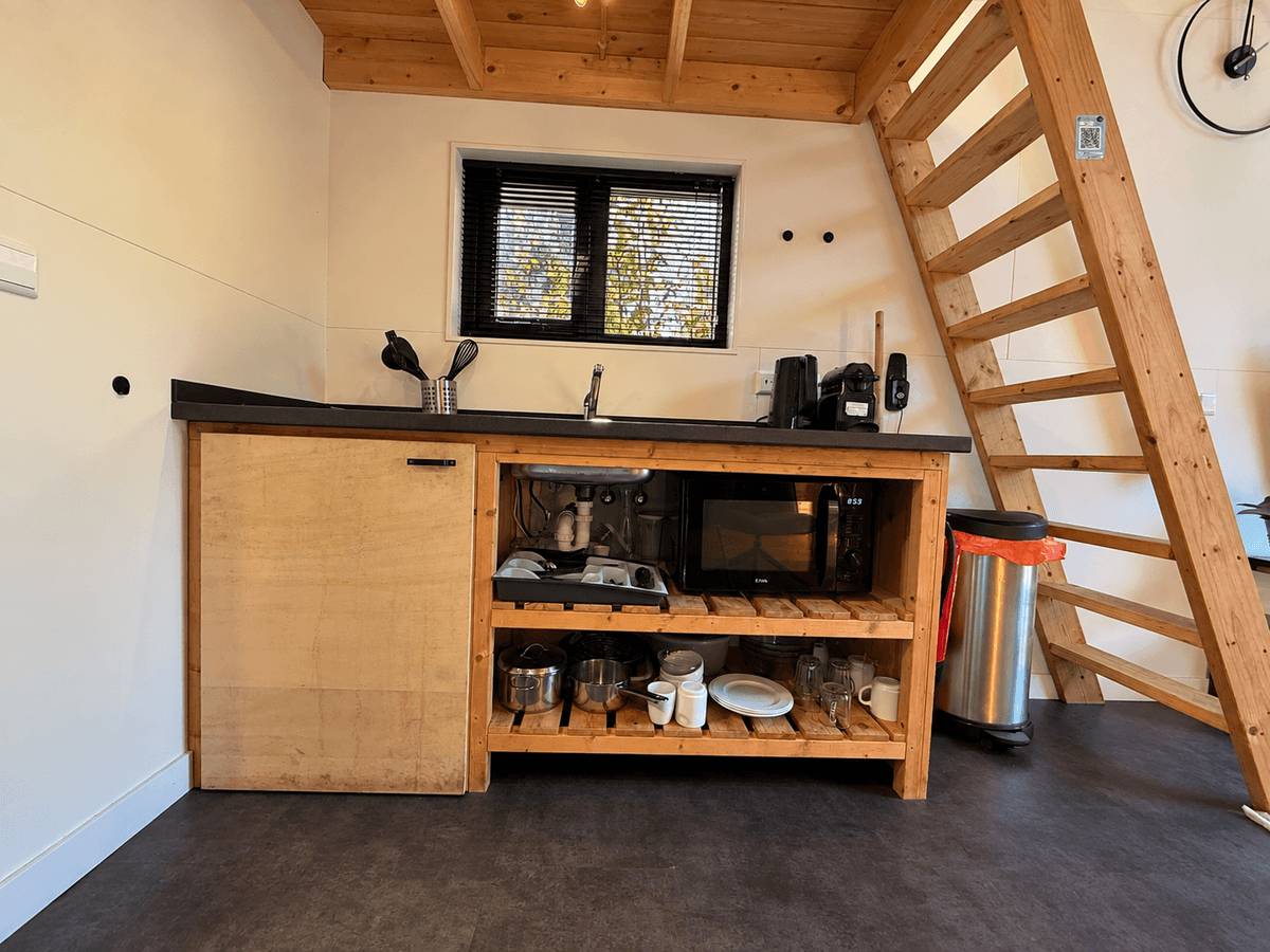 Keuken in een recreatiewoning met houten kasten, een spoelbak, een fornuis en een trap naar een bovenverdieping.