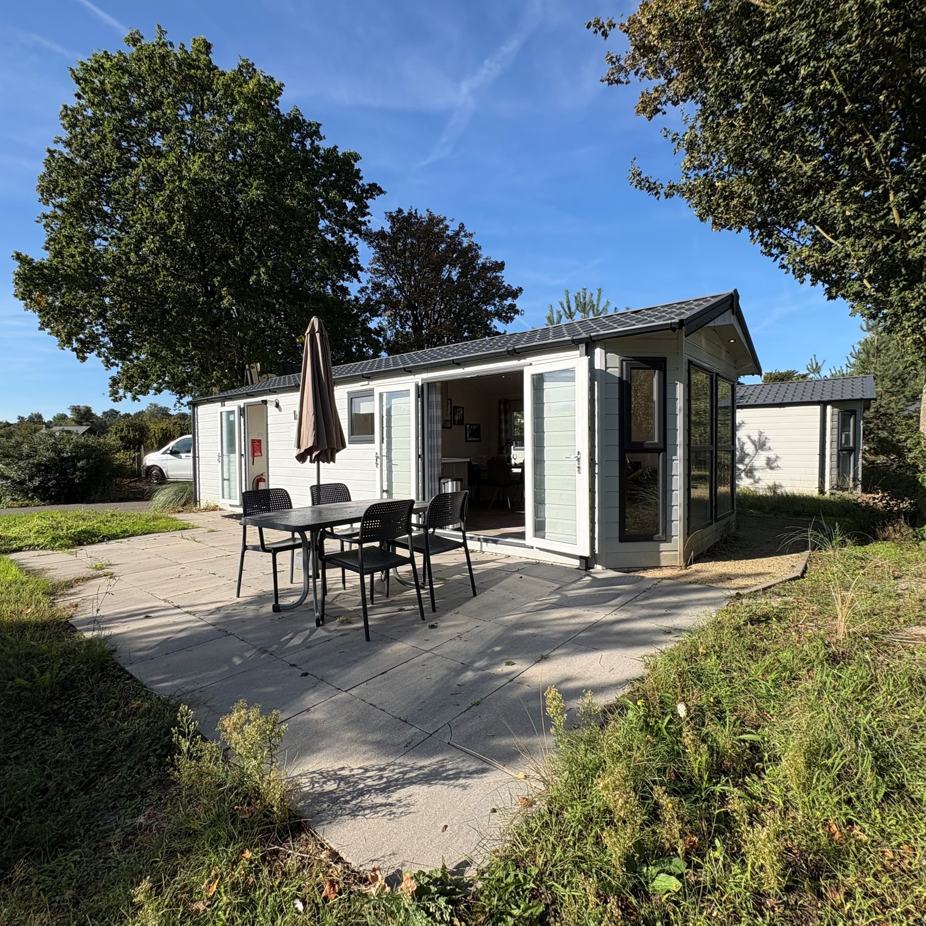 Recreatiewoning met terras en tuinmeubilair, omringd door groen en bomen, op EuroParcs Zuiderzee.