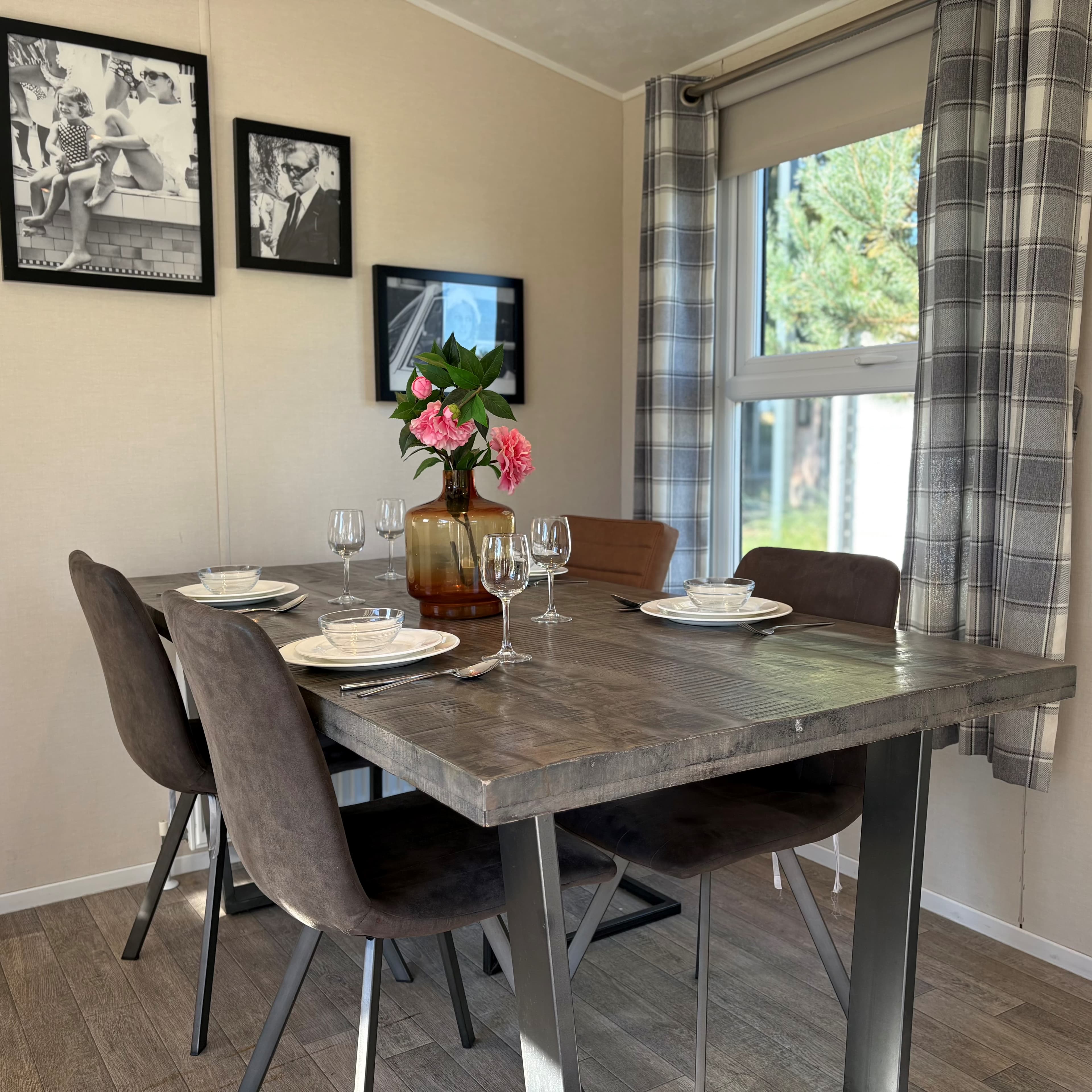 Eettafel met vier stoelen, vazen met bloemen en foto's aan de muur in een lichte ruimte bij EuroParcs Zuiderzee