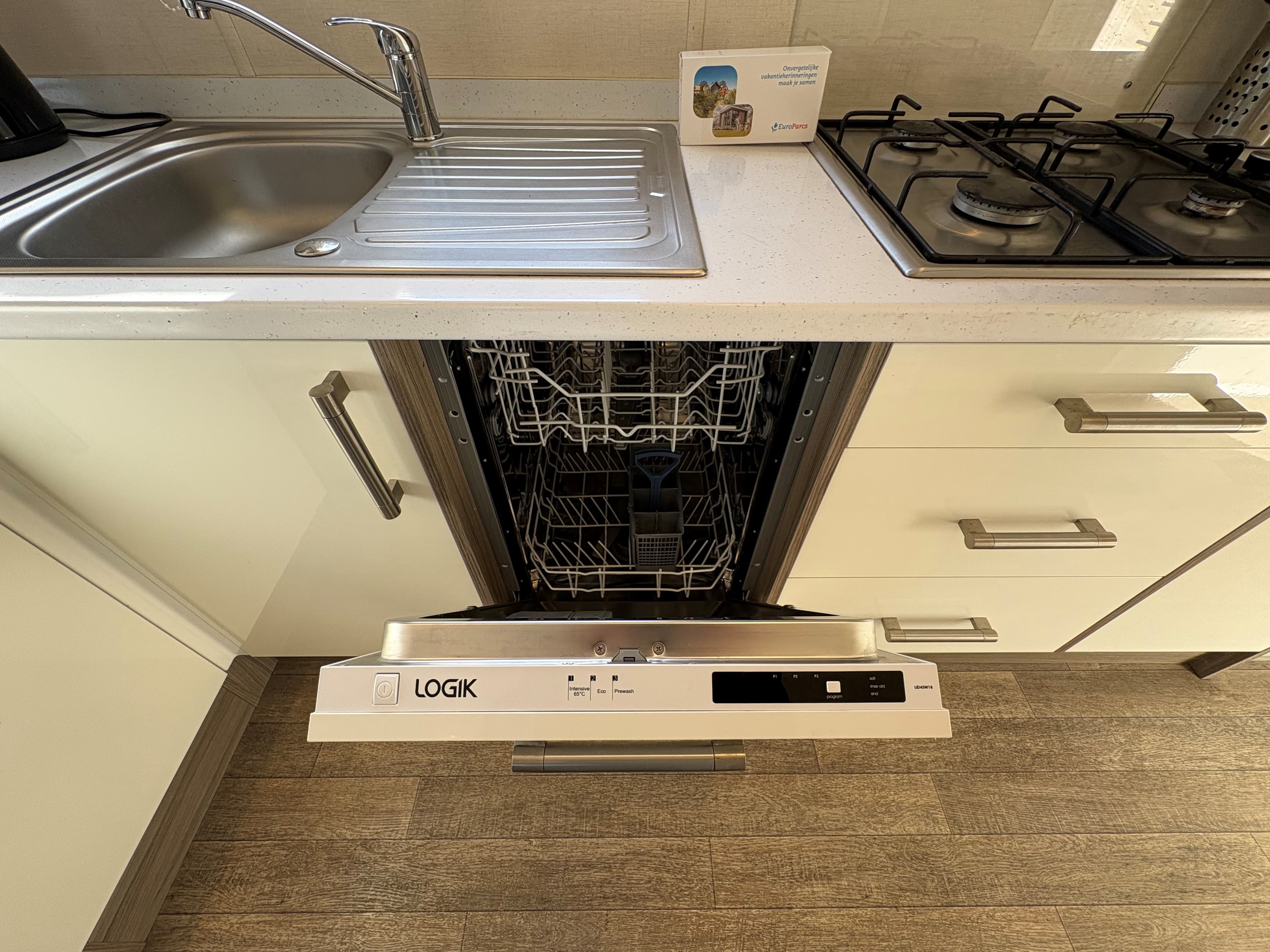 Keuken met een open vaatwasser en een gasfornuis, keukenblad en moderne keukenkasten zichtbaar