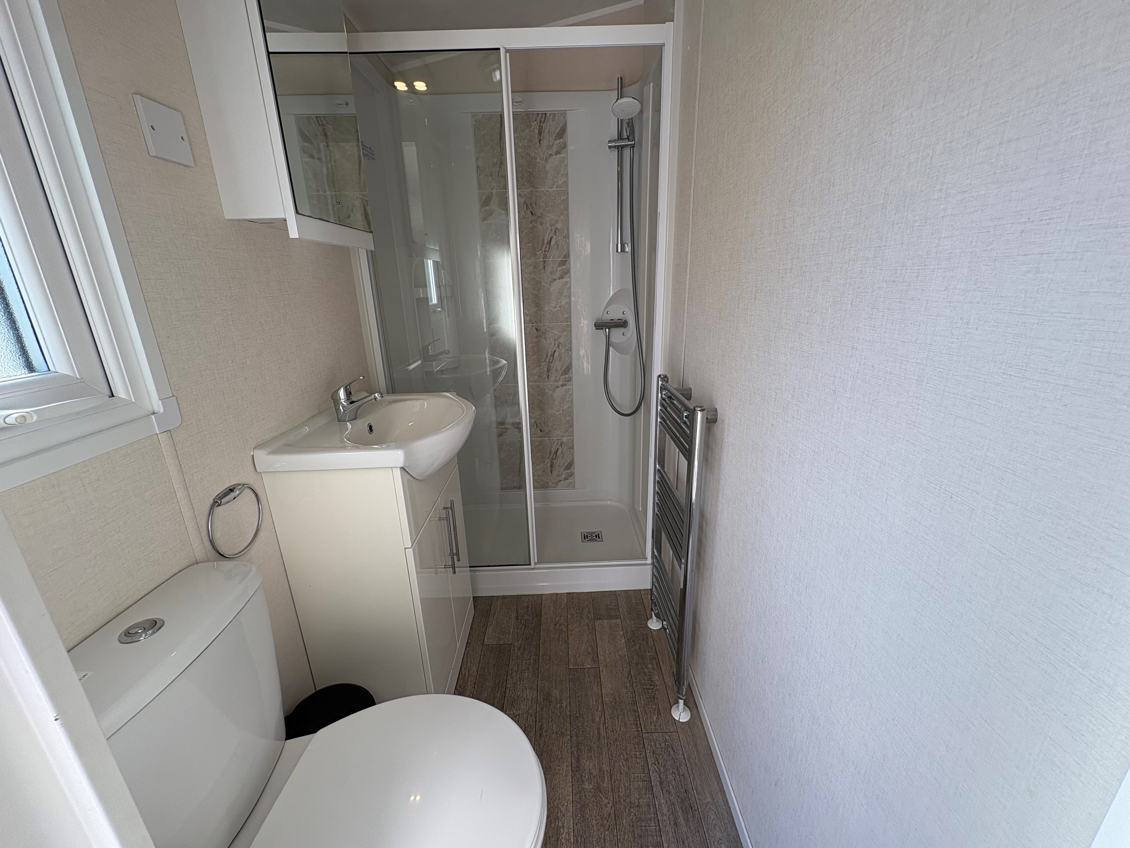 Badkamer met douchecabine, wastafel, toilet en handdoekenradiator in lichte, moderne stijl