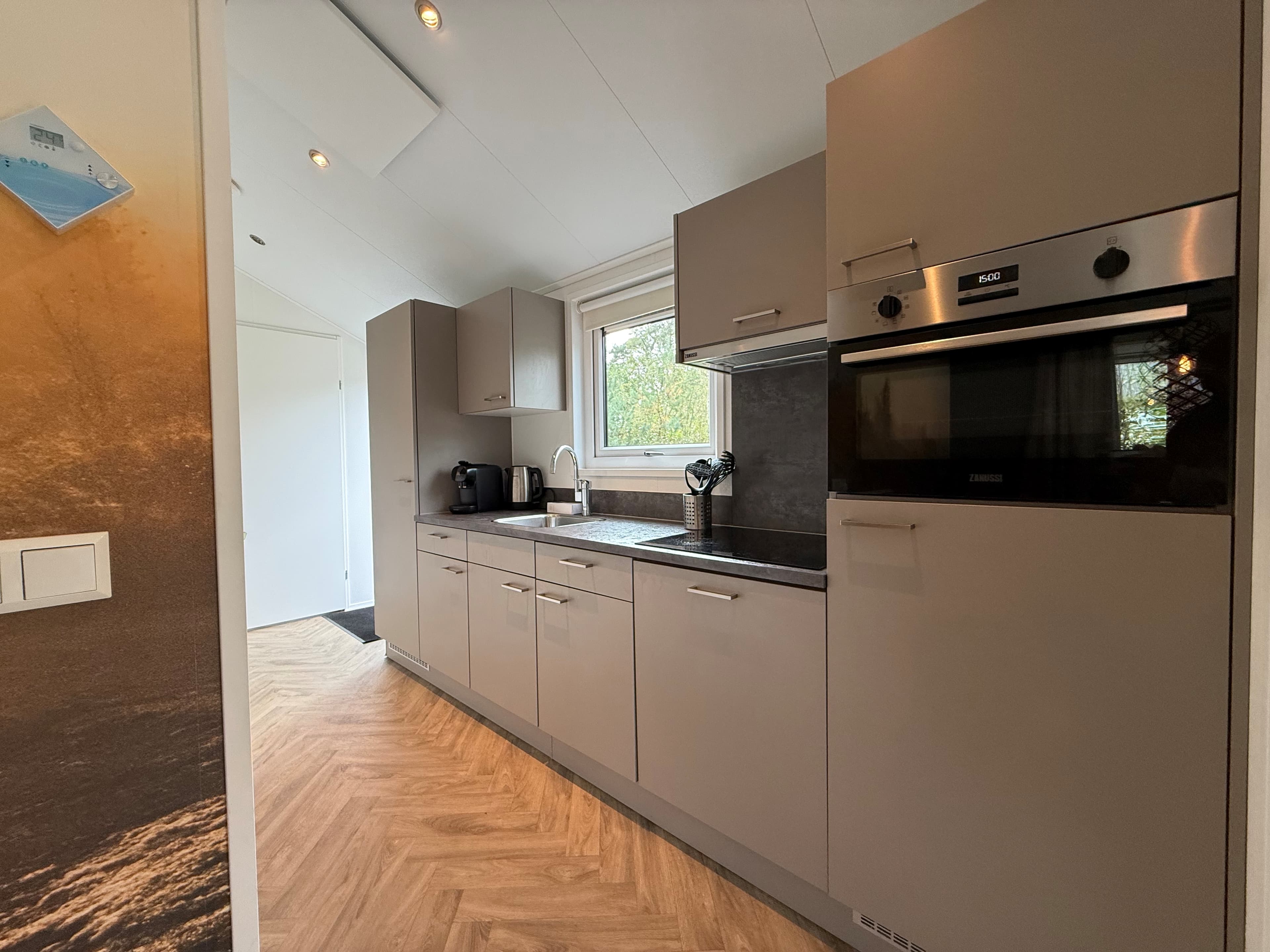Moderne keuken met grijze kasten, werkblad en inbouwapparatuur, geschikt voor een recreatiewoning.