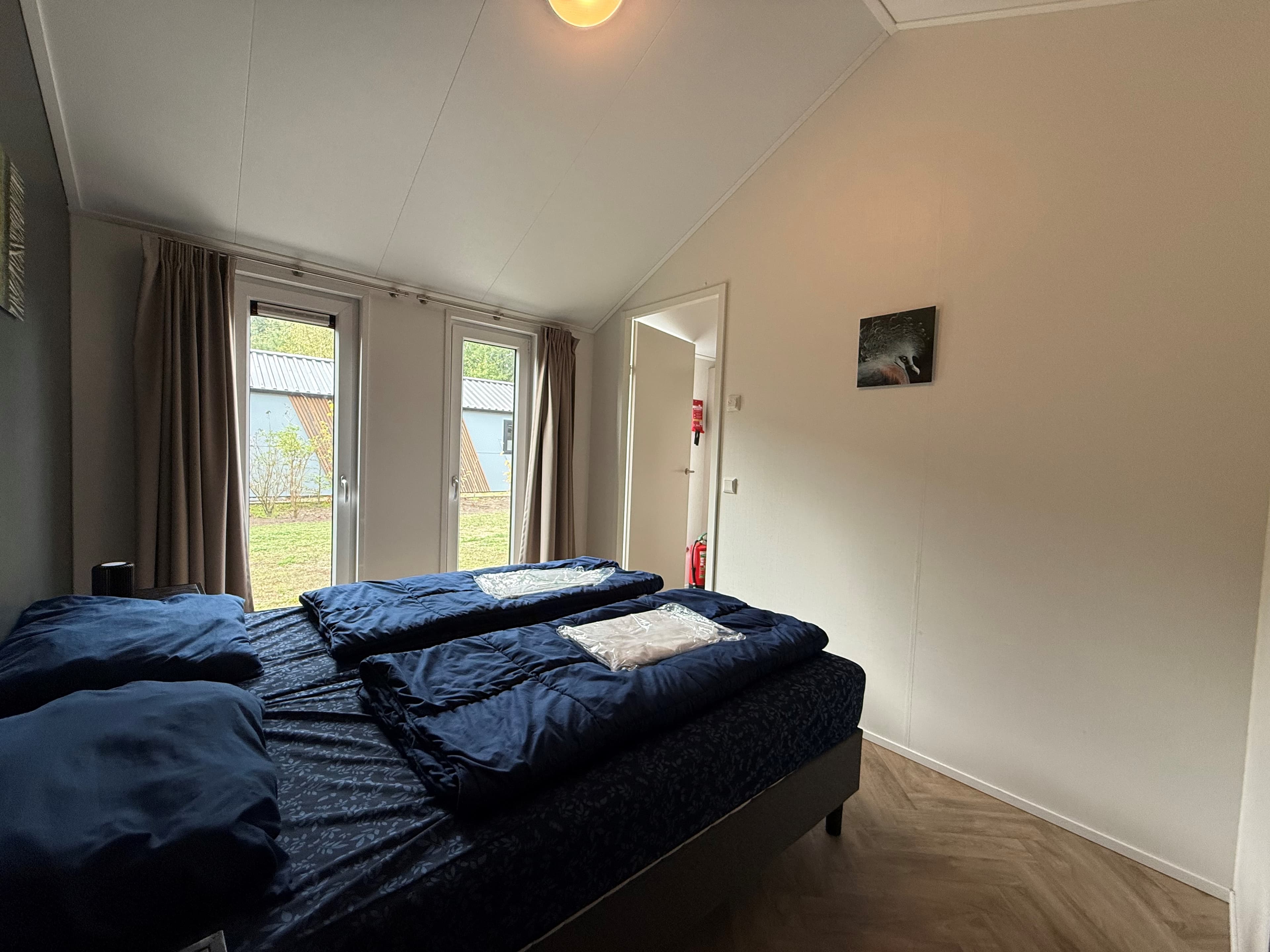 Slaapkamer met twee aparte bedden, ramen met uitzicht op de buitenruimte en een neutrale inrichting