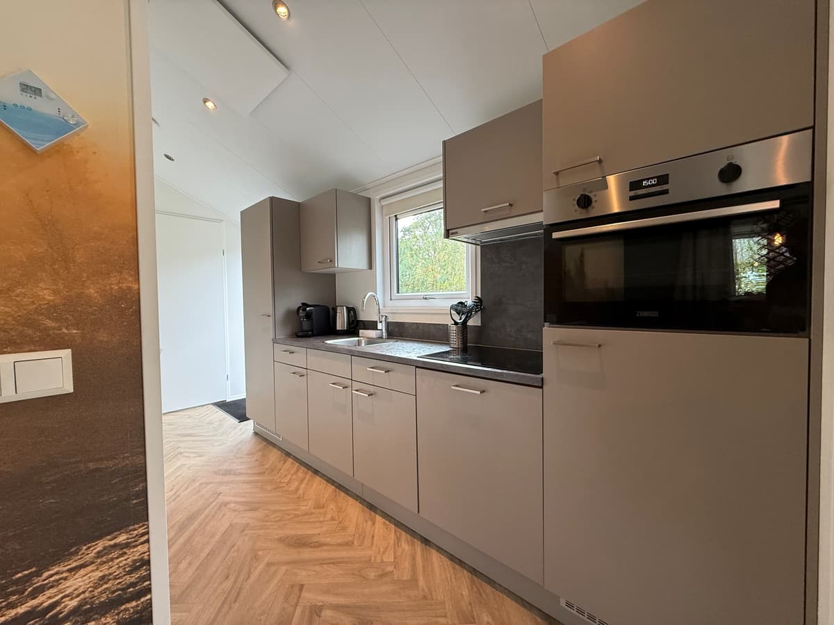 Moderne keuken met grijze kasten, werkblad en inbouwapparatuur, geschikt voor een recreatiewoning.