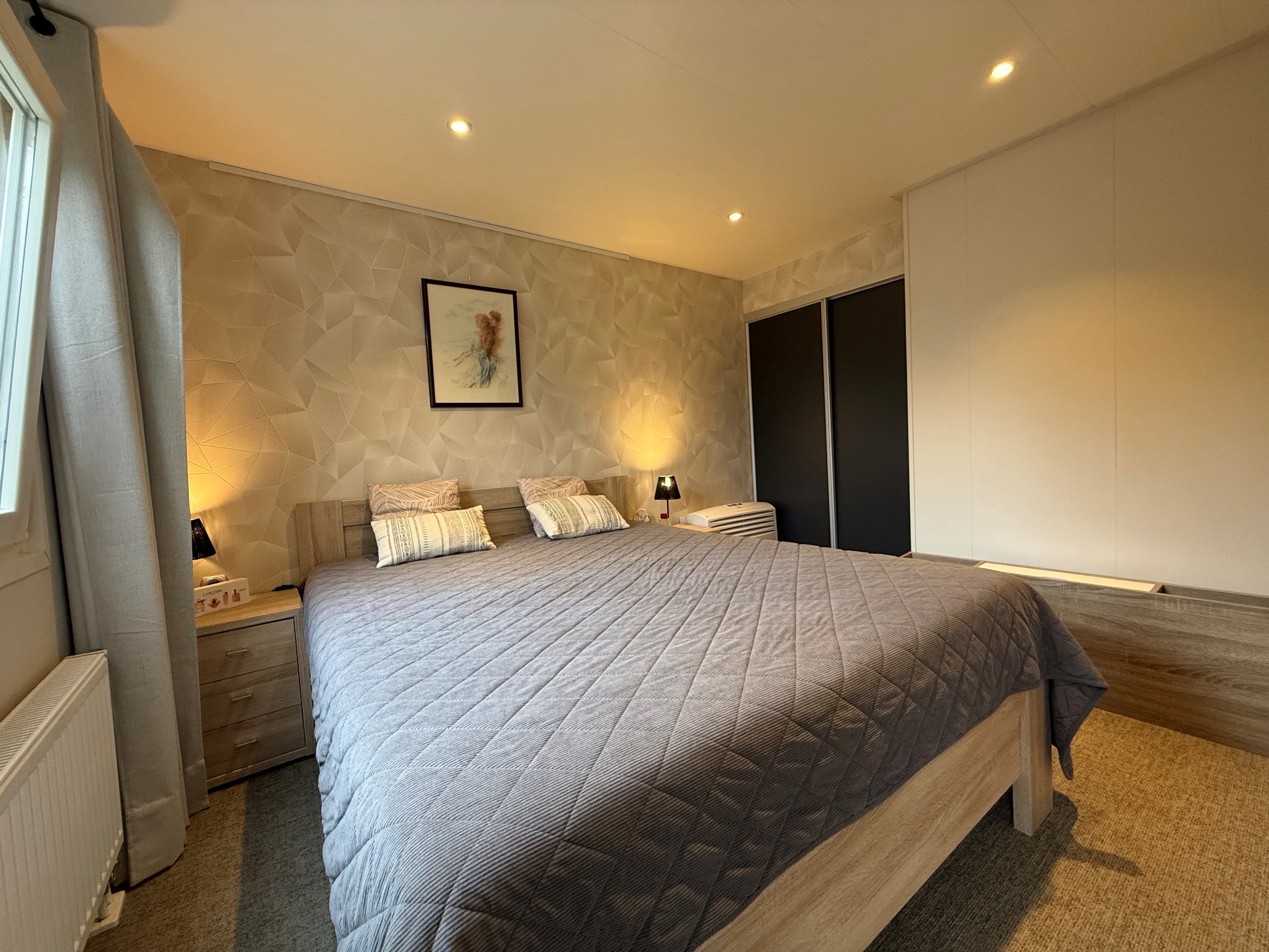 Slaapkamer met een tweepersoonsbed, nachtkastjes en een inbouwkast aan de muur