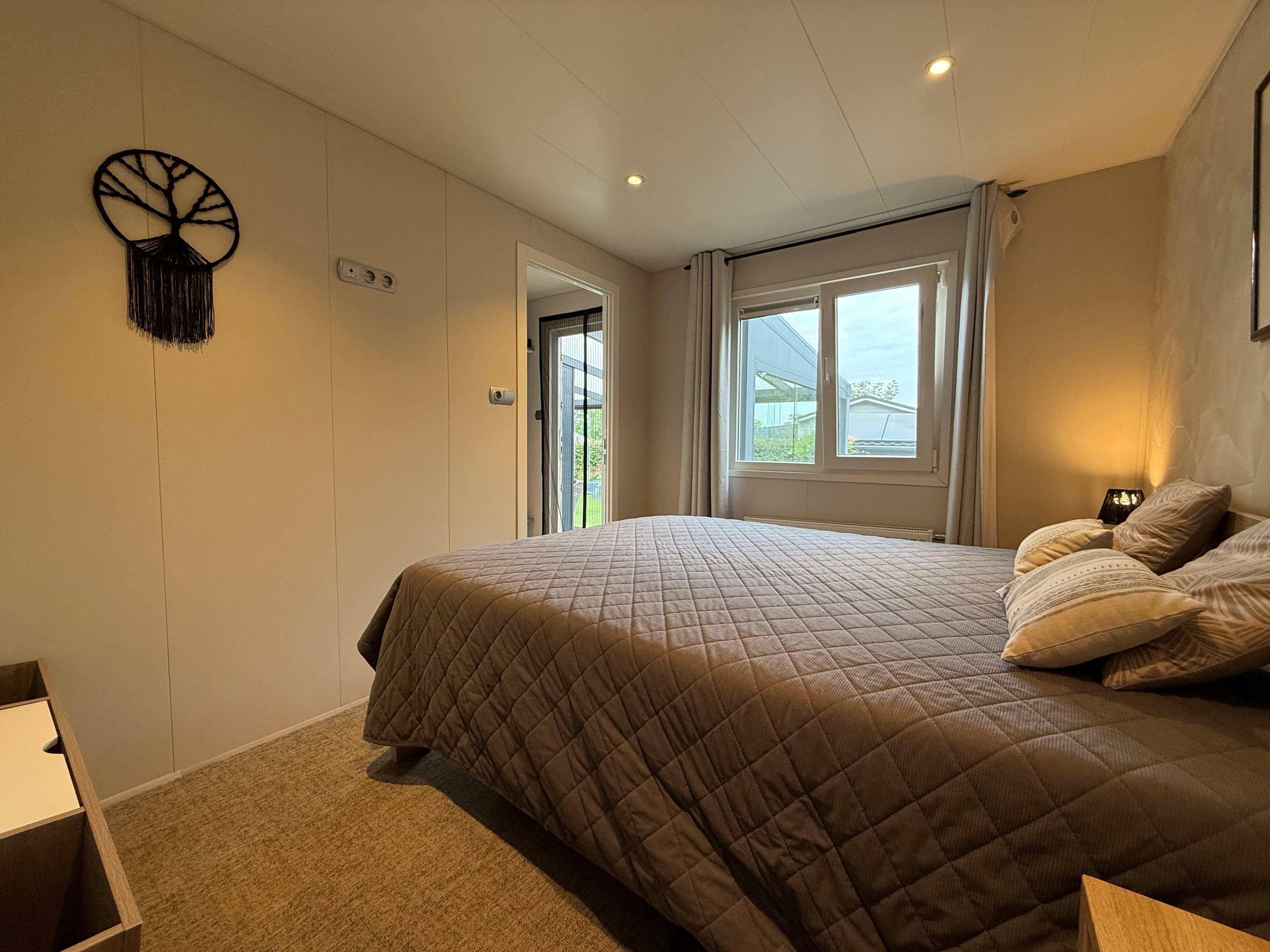 Slaapkamer met een groot bed, raam met uitzicht op buiten en een wanddecoratie aan de muur
