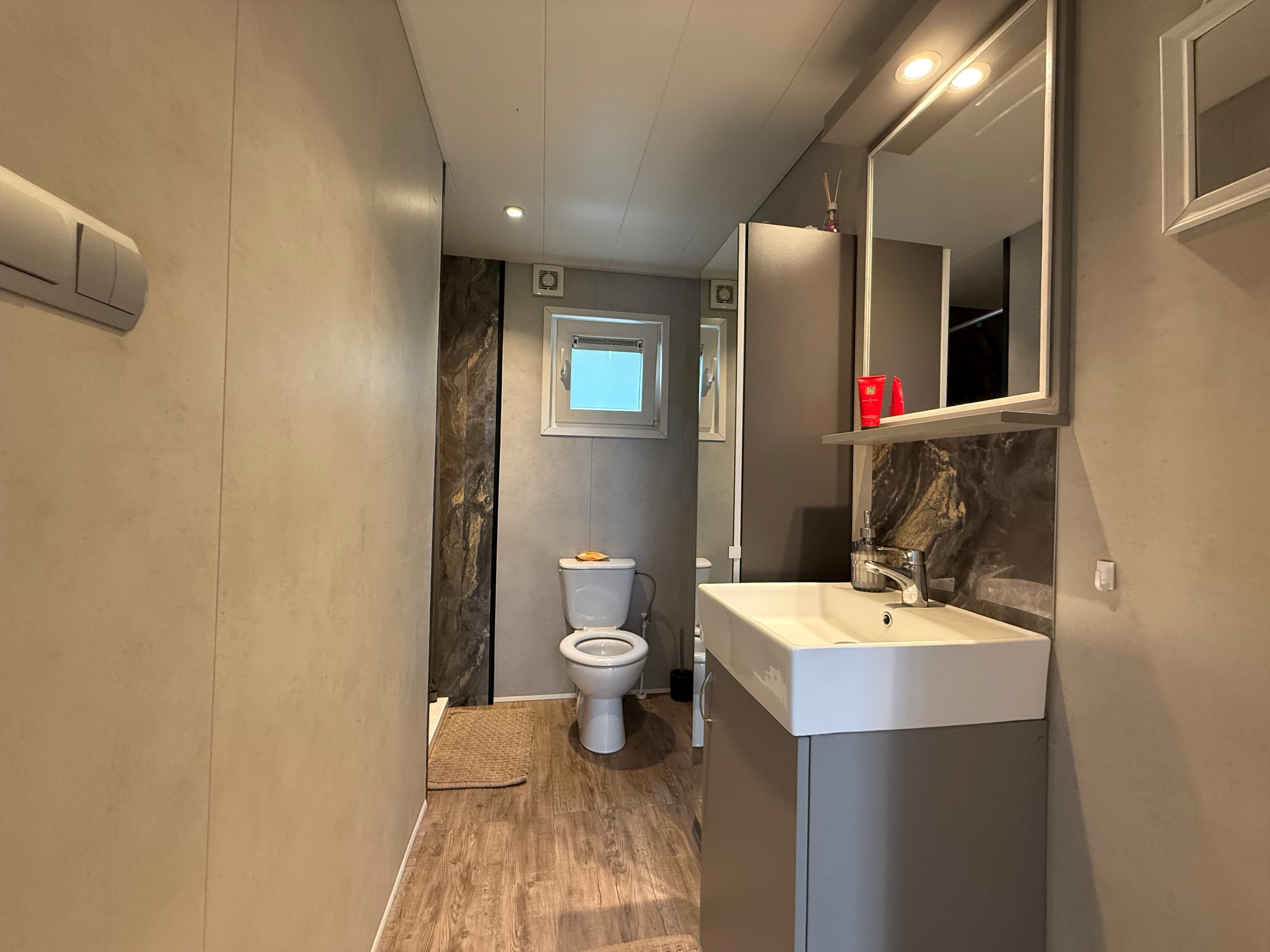 Badkamer met toilet en wastafel, stucwanden en moderne afwerking, ingetogen kleurstelling en verlichting