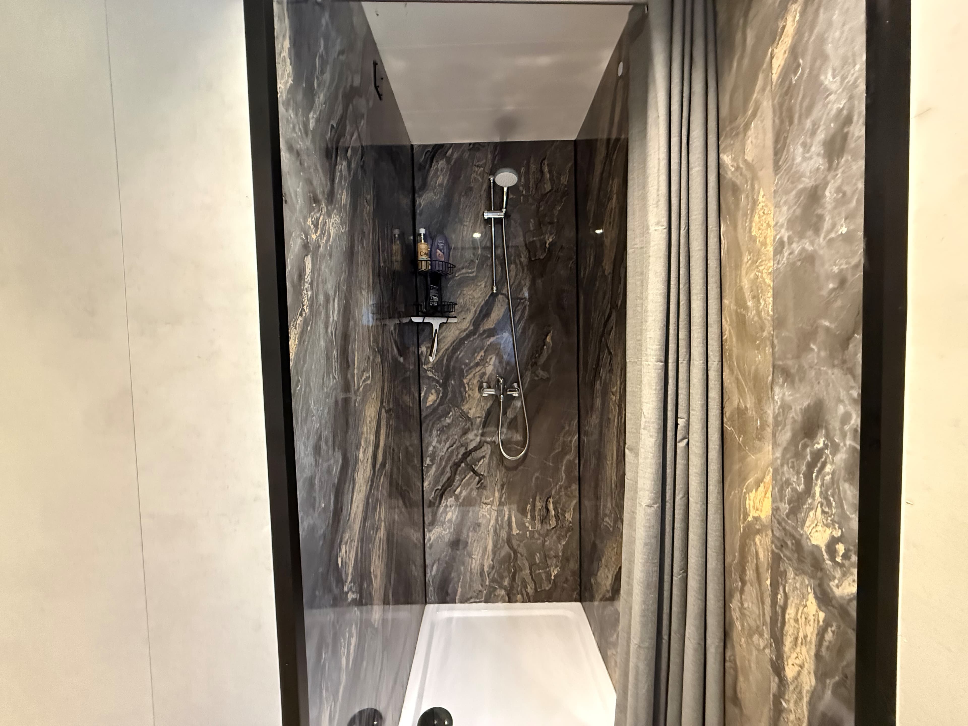 Inloopdouche met marmeren wanden, regendouche en wandplank voor toiletartikelen